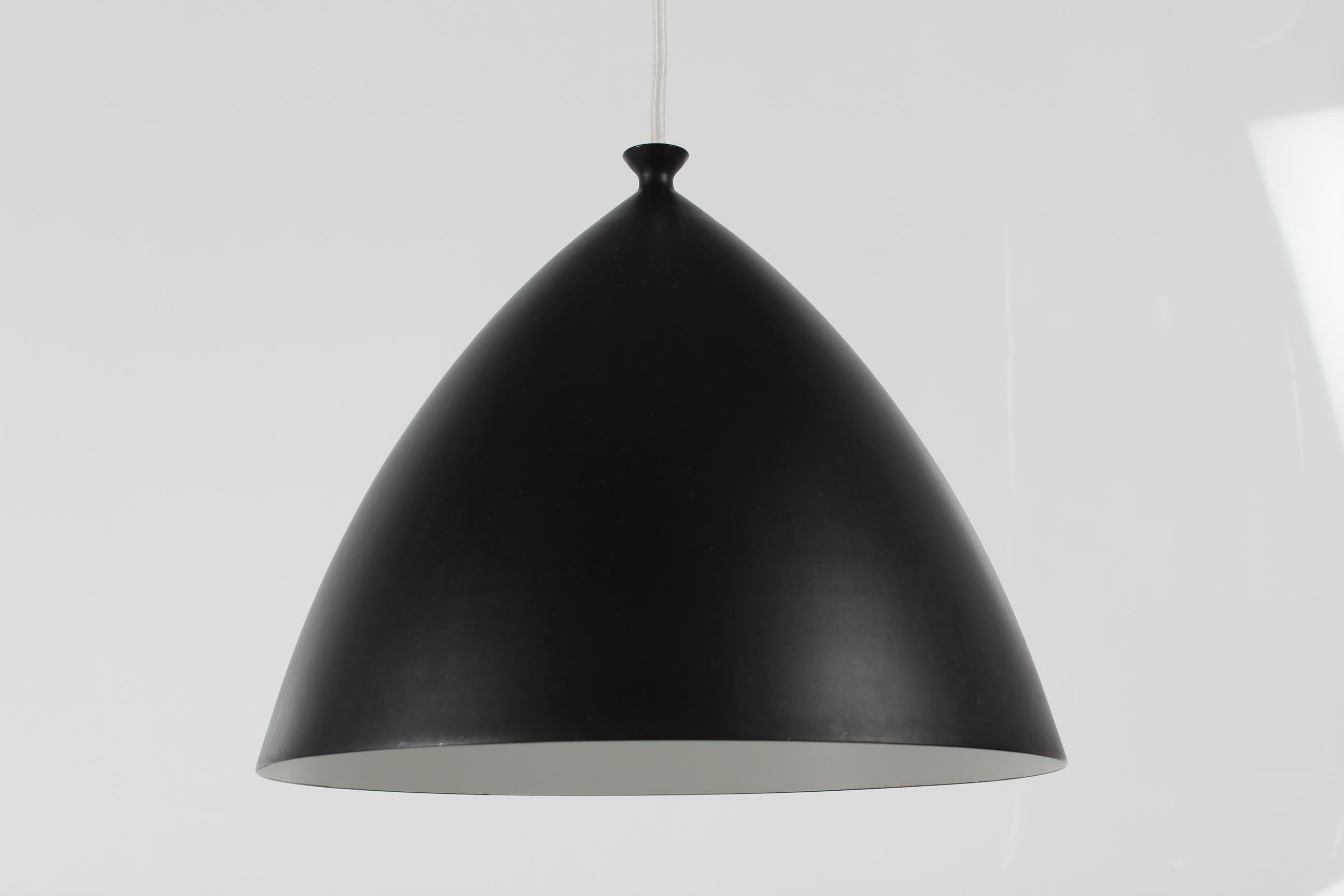 Vintage Scandinavian pendant manufactured ca 1960s.

The lamp is shaped like a beautiful taut arc with a nice detailing on top like an open mouth. It's black on the outside and white on the inside. Perfect over a dining table.

The designer and