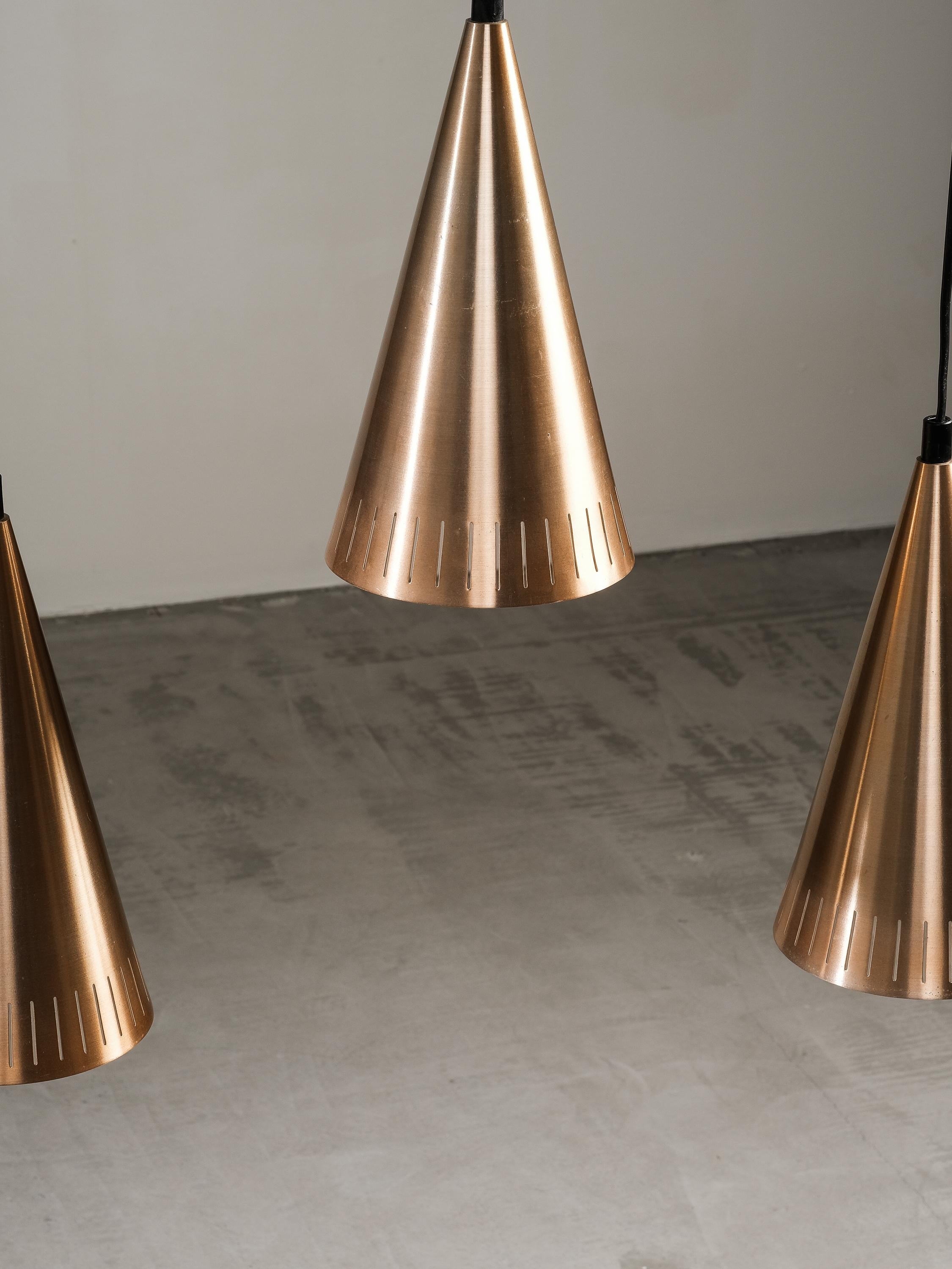 Affascinante lampada a sospensione scandinava di metà secolo. La lampada è composta da tre pendenti in alluminio color rame collegati a un divisorio in teak.