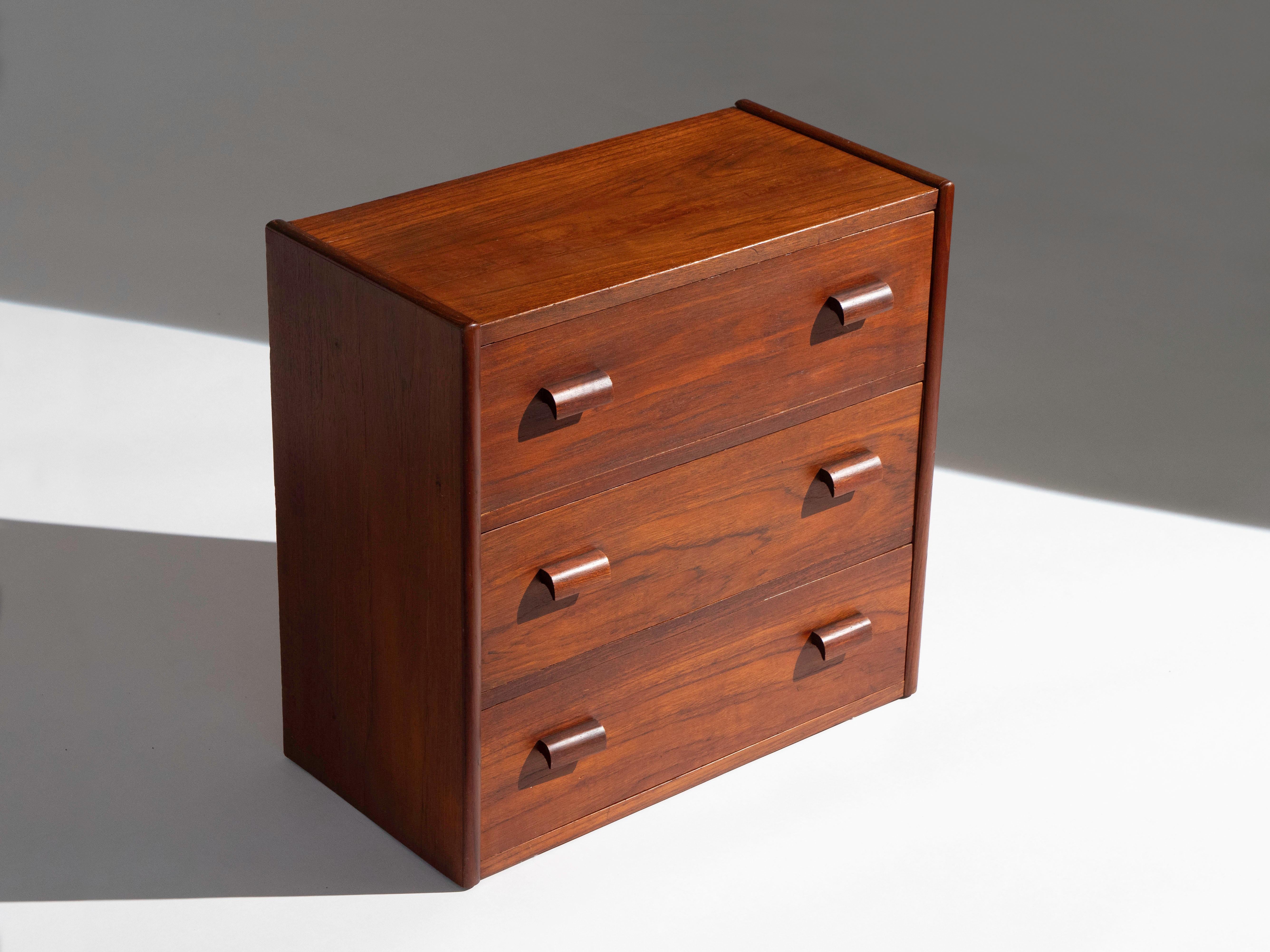 Scandinavian chest of drawers in old growth teak with solid teak handles. The cabinet contains three drawers -- interiors are comprised of solid oak. The cabinet is in very good vintage condition with a nice patina that's consistent with age. It is