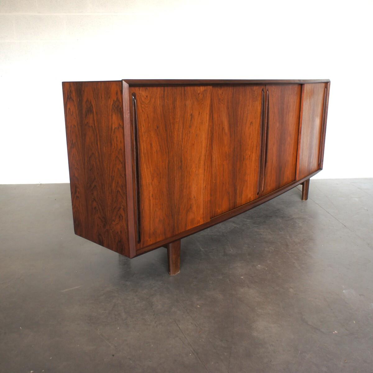 Scandinavian sideboard made of rosewood from Rio. It's facade is slightly curved (galbée) making it quite exceptional. It has four sliding doors opening onto a spacious storage, and a bar on the left side with four cutlery drawers. 