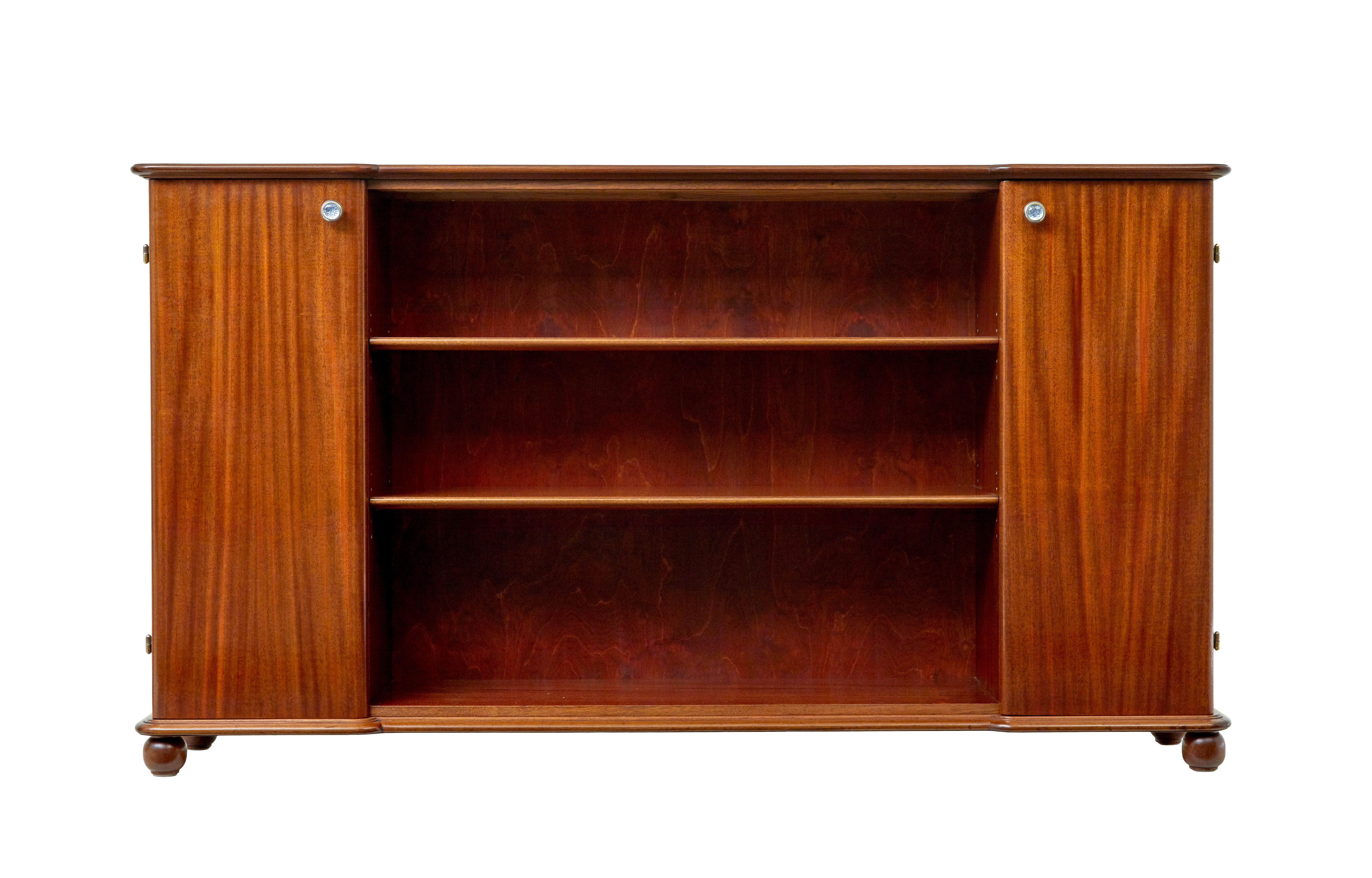 Credenza scandinava di metà secolo con libreria del 1970 circa.

Elegante credenza/libreria aperta di produzione svedese, impiallacciata in mogano.

La superficie superiore presenta una leggera frattura, mentre il deposito principale dei libri si