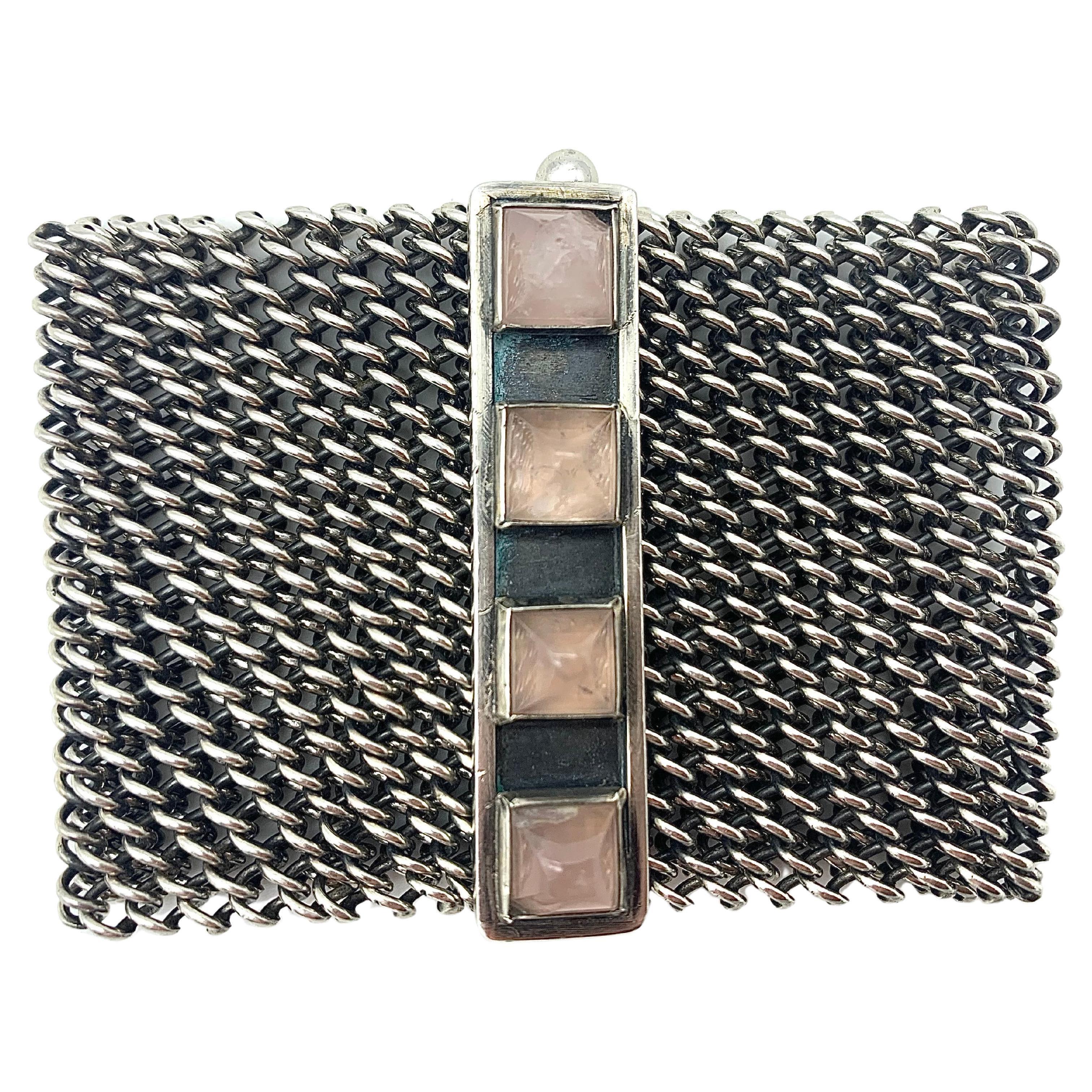 This wonderfully smooth silver mesh bracelet was created in 1960 ca. 
The bracelet is marked 835, a silver content mark used in Scandinavia. The ornamental bracelet clasp is set with four rose quartz sugarloaf  cabochon. The two outer stones have