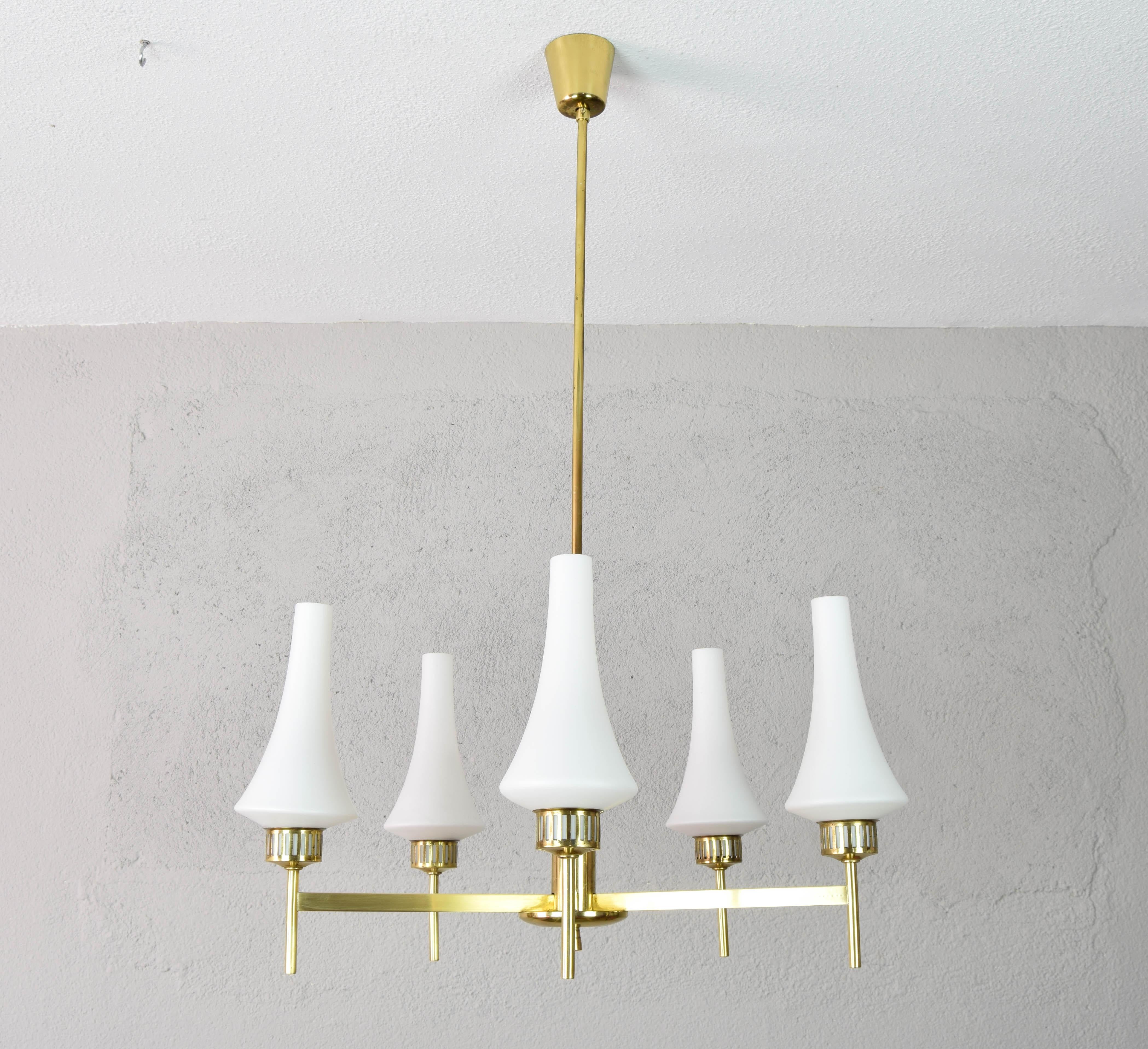 Beautiful Swedish chandelier from the 1950s. Its brass body has five arms with opaline lampshades.
Similar in style to Kaiser's brass chandeliers, it has a characteristic delicacy and elegance.
The chandelier presents in the brass finish marks of