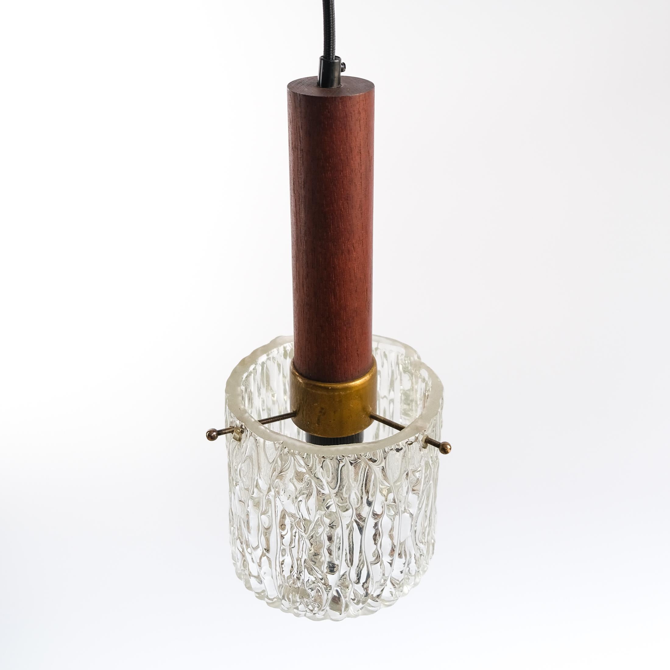 For sale is a Mid-Century Modernist Scandinavian Teak, Brass & Textured Ice-Glass Pendant Light, dating from circa 1960s.

In good working order, with its original teak ceiling rose and re-wired with a black braided cloth cord. The light is in fair