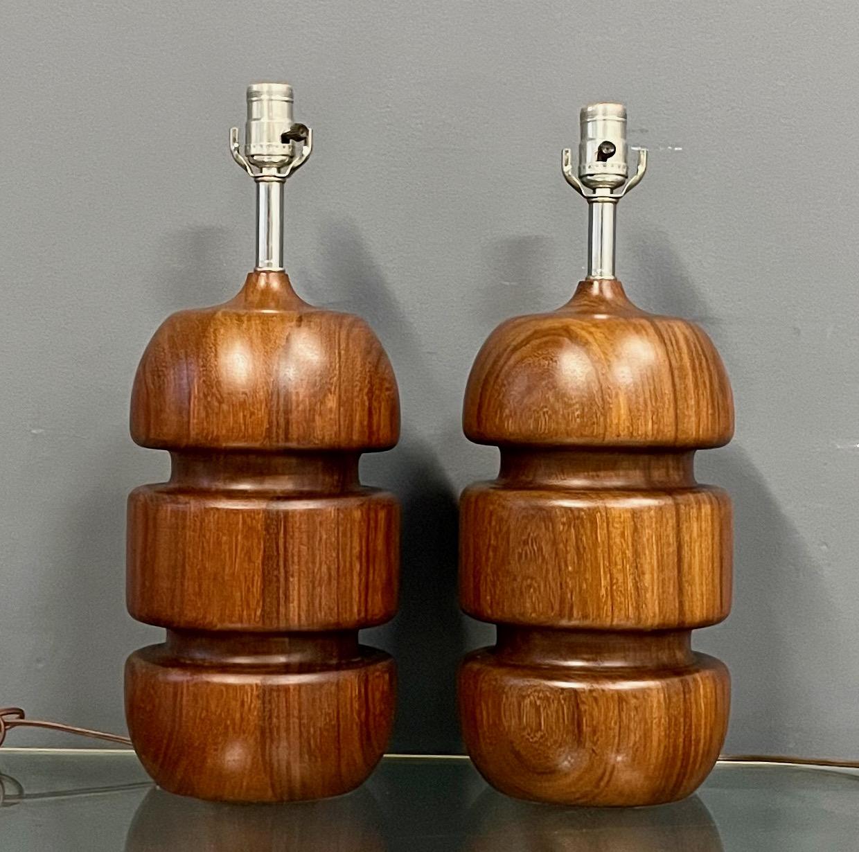 Wonderful pair of turned lamps in teak and are a classic of mid century design. These lamps have a wonderful oiled finish.