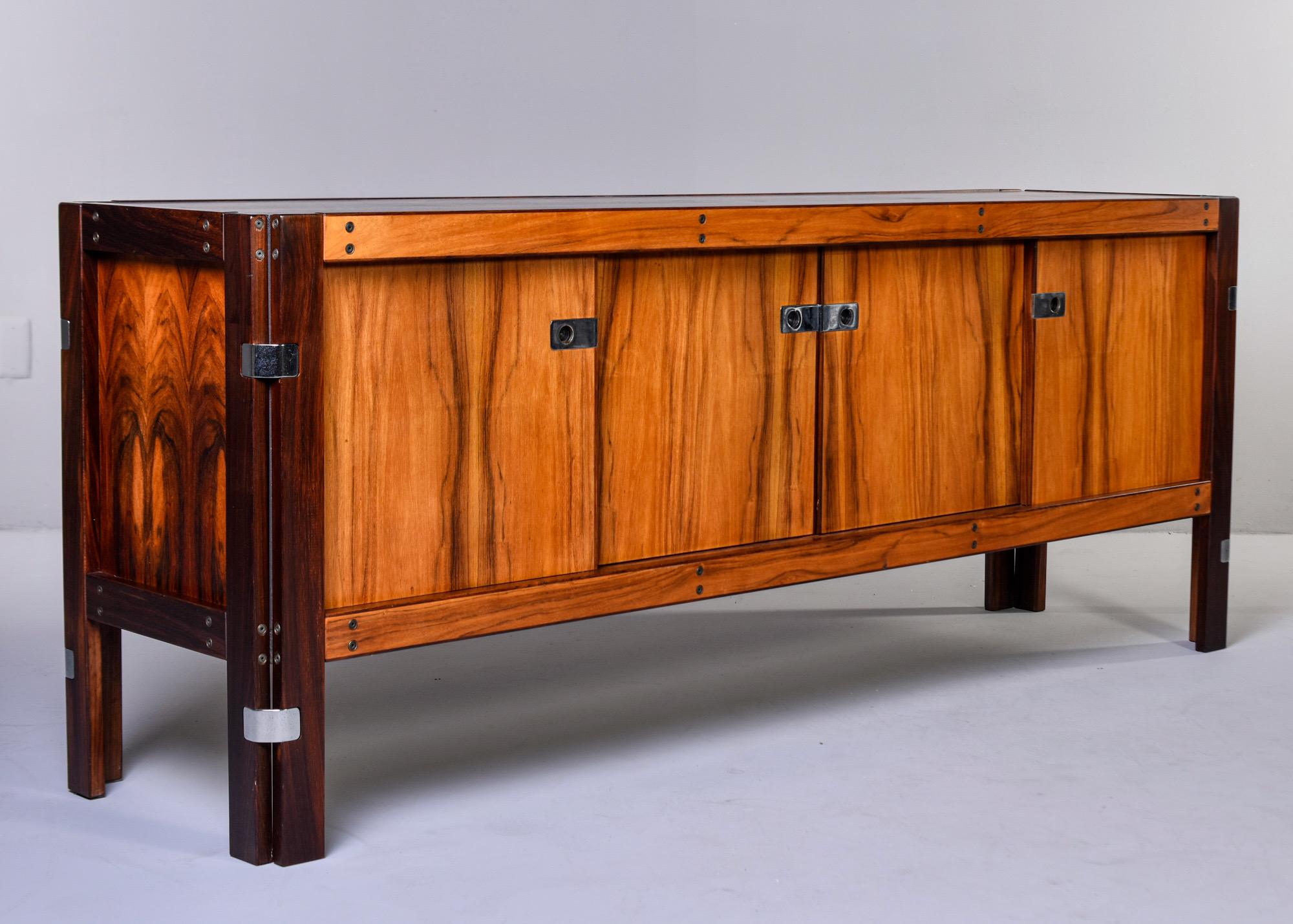 Scandinavian buffet or credenza in dark and lighter contrasting rosewood with polished nickel hardware, circa 1970s. Four sliding doors with outer two compartments having single internal shelf and inner two compartments having two drawers each and a