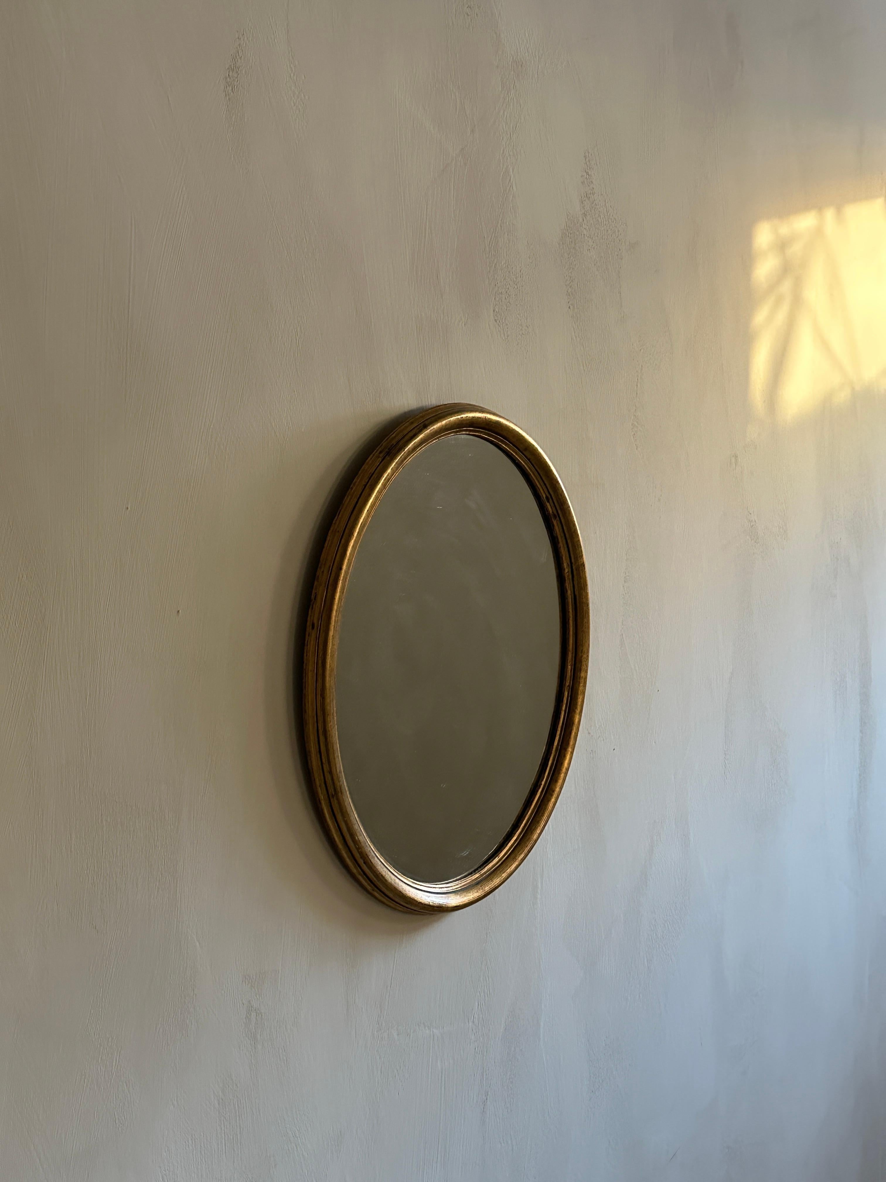 Mid-century Scandinavian wall mirror designed by unknown artist. Original unrestored mirror with golden frame, circa 1930/40s. Very elegant and characteristic egg shape. 

Wear due to age and use with some patina on the glass. Stains.
