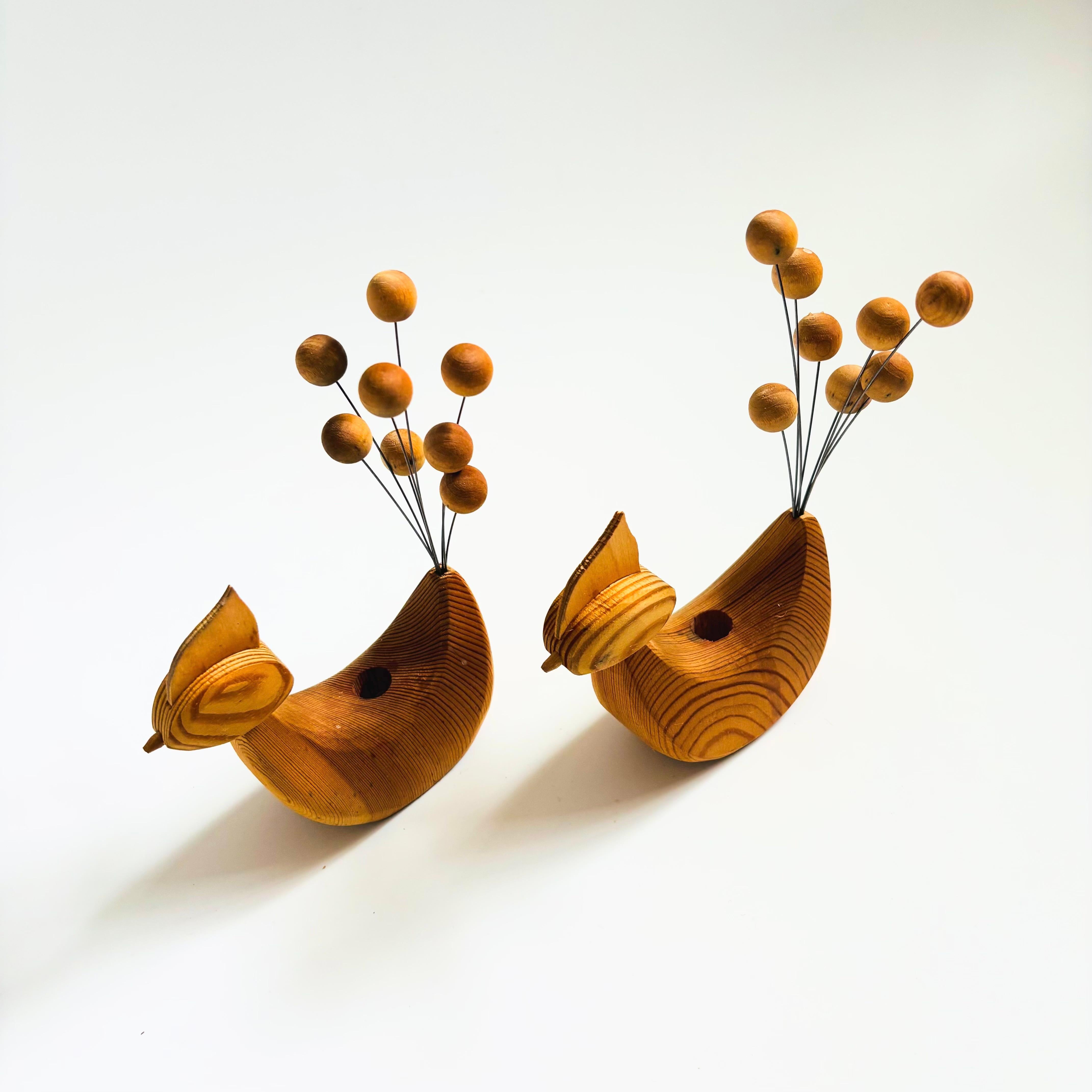 A set of 2 mid century Scandinavian folk art wood bird candle holders. Each with a kinetic tail made of thin metal rods and wood balls. Simplified features carved into the wood with a hold in the center for holding a tiny taper candle. 


