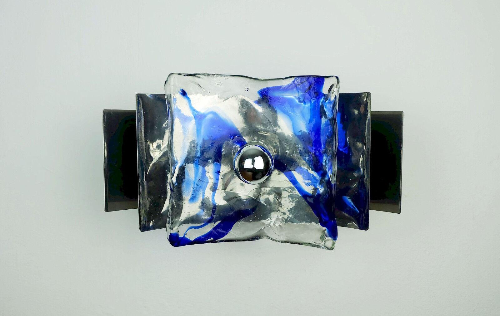 A very beautiful 1960s to 70s mid century wall lamp. No label, origin most probably Italy. It consists of 2 rectangular curved sheets made of chromed metal and a curved square disc made of thick transparent ice glass with blue inclusions. Holds 1