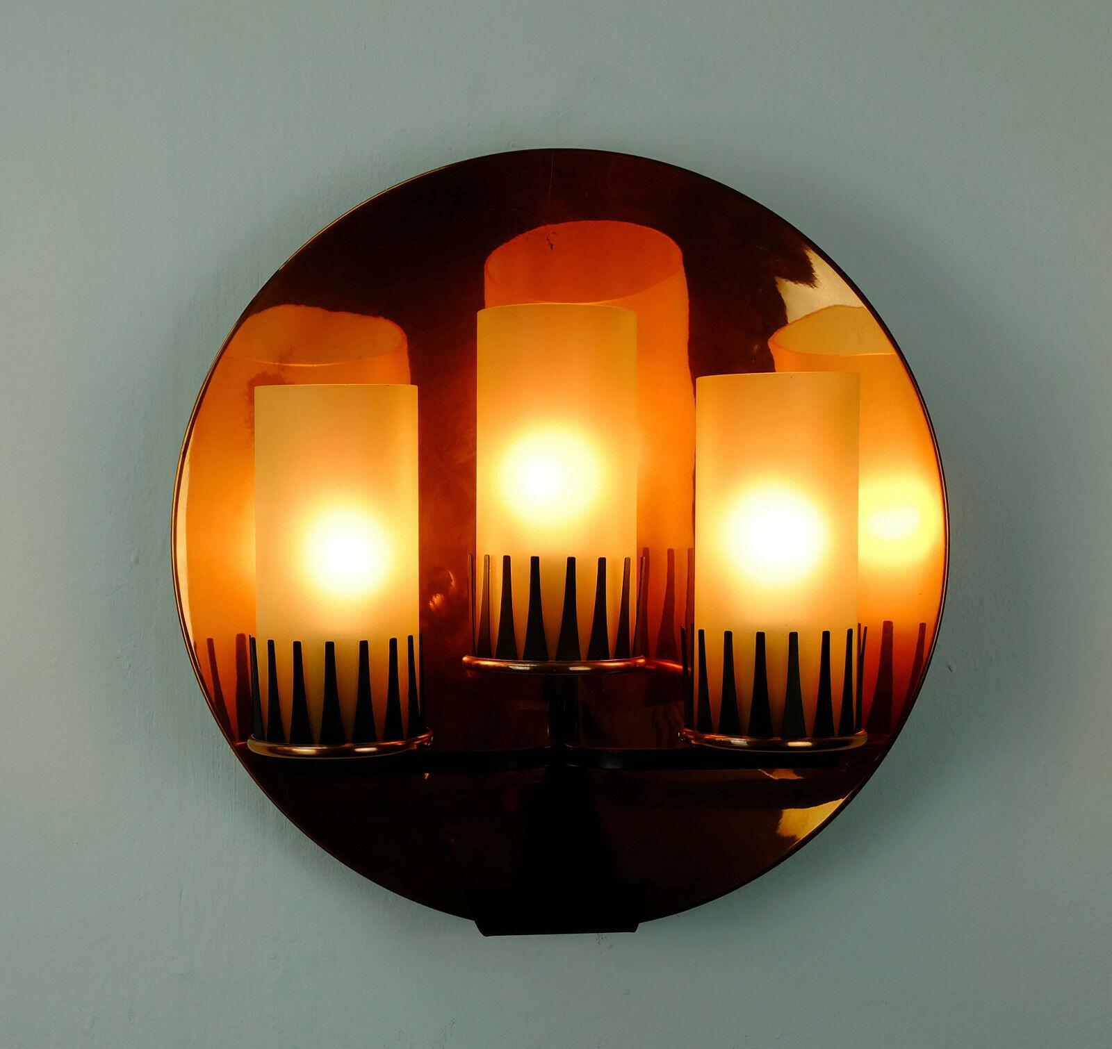 Fantastic 1950s to early 1960s wall lamp. The base is a round concave copper disc. It holds the frame which is made of black metal and copper. The shades are made of yellowish matte glass. 

Good condition, no damages at the glass, some wear at