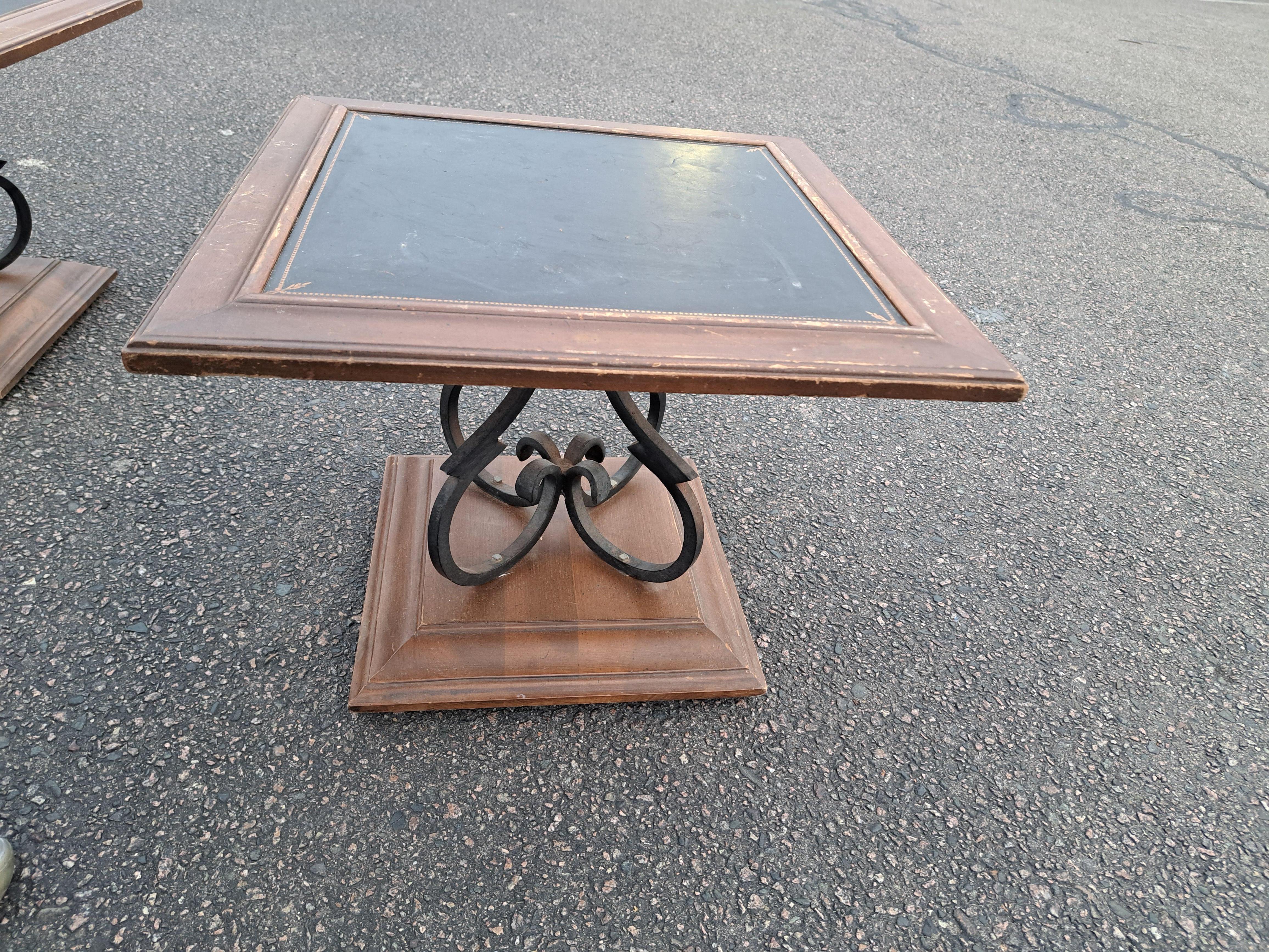 Pair of vintage low side tables with scrolled wrought iron bases and wood and leather top. Table tops swivel.