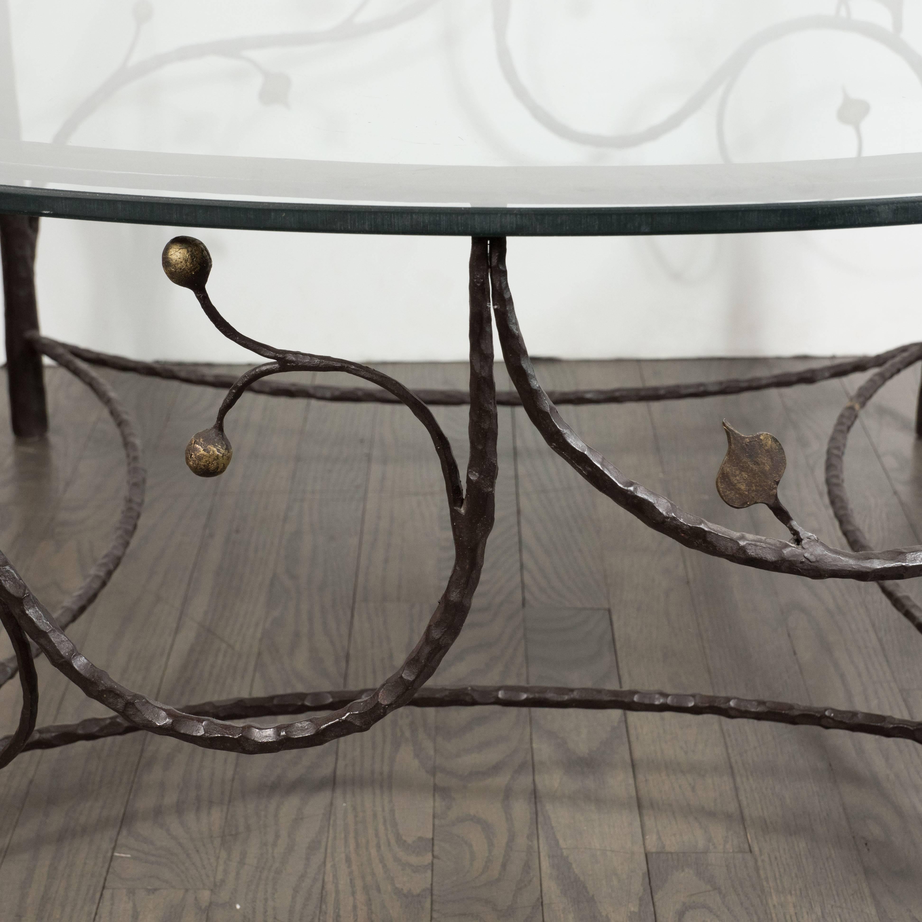 This whimsical yet sophisticated coffee table was realized in the United States, circa 1960. It features four legs that taper to their apex- resembling the form of conifer trees- which support a circular glass top. Scrolling arms culminating in