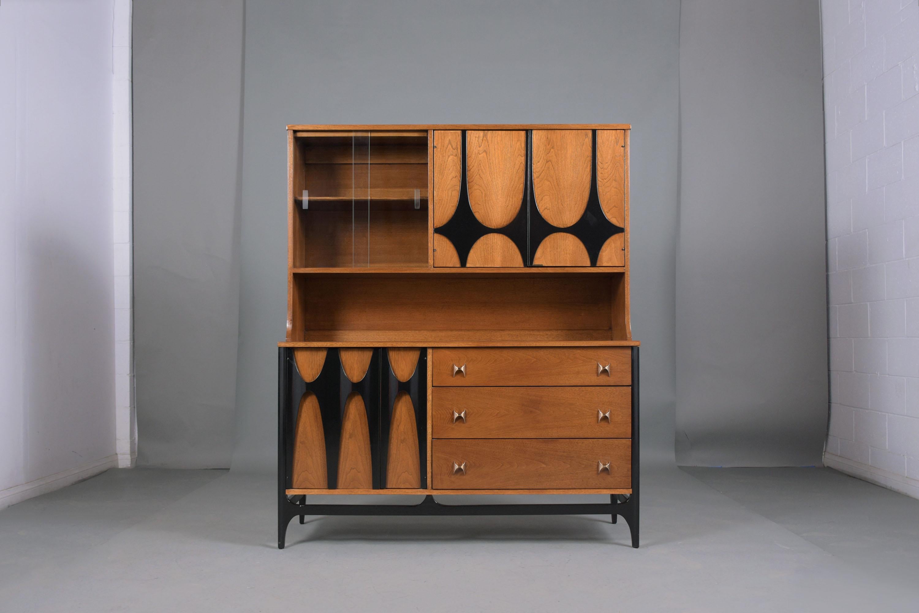 An extraordinary 1960s Broyhill Brasilia credenza/server has been professionally restored by our team of in the house craftsmen. This credenza features an intricate sculptural carved design, and an elegant walnut & ebonized color combination with a