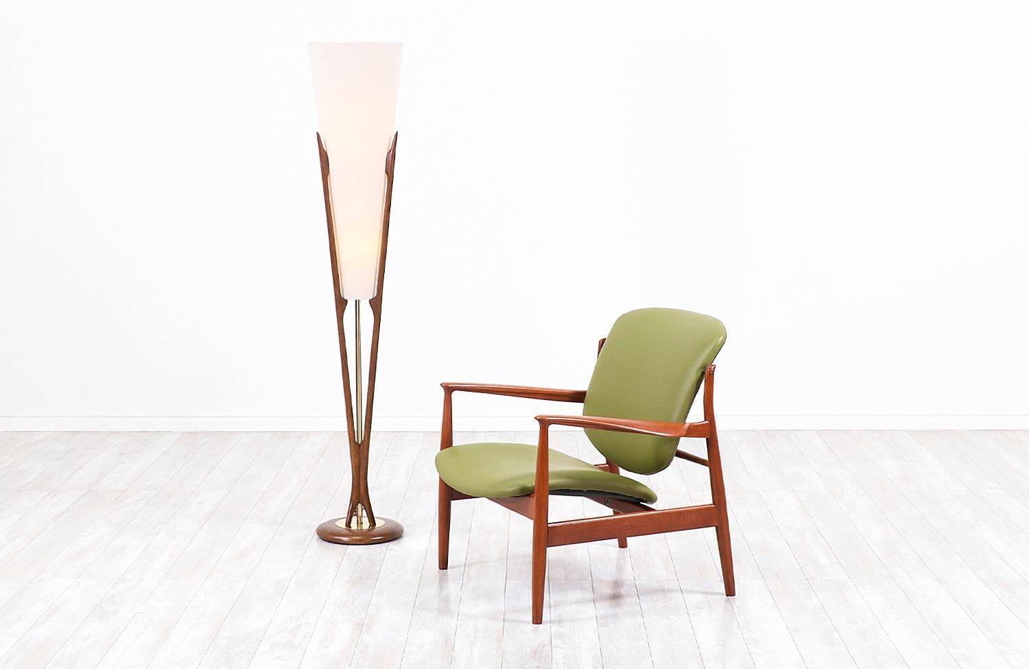 Stunning sculpted modern floor lamp designed and manufactured by Modeline of California in the United States, circa 1960s. This rare floor lamp is comprised of a carved walnut wood frame that connects from the top to the rounded base creating a ‘V’