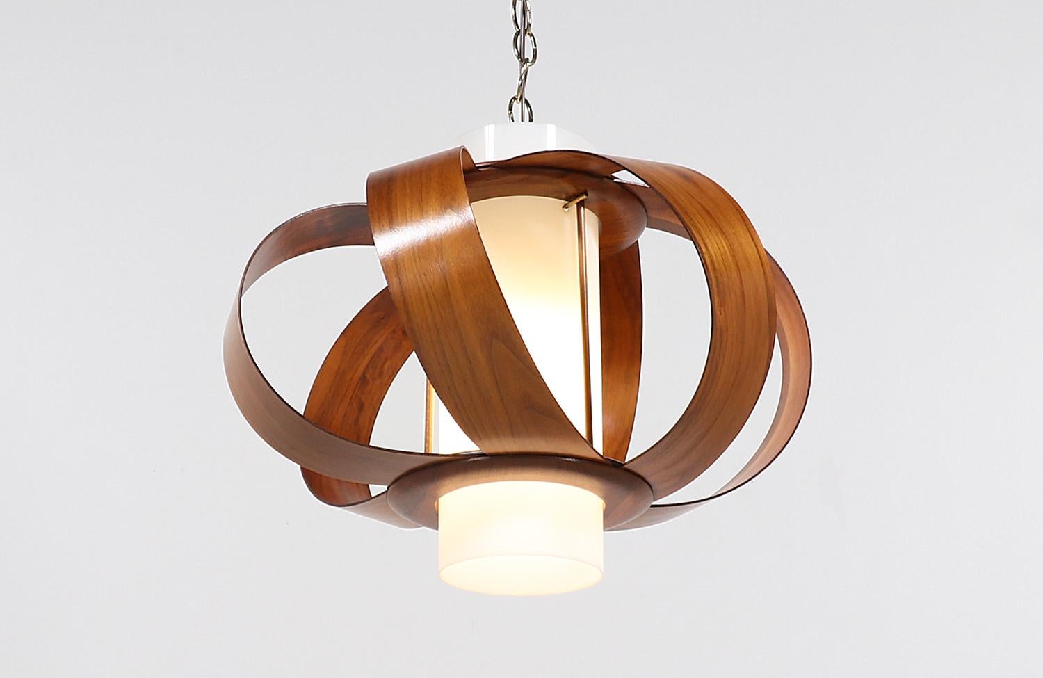 Dazzling Mid-Century Modern sculpted chandelier designed and manufactured circa 1960s. This rare and delicate chandelier features walnut bentwood leaves, creating a spherical effect around the original cylindrical glass shade that makes this