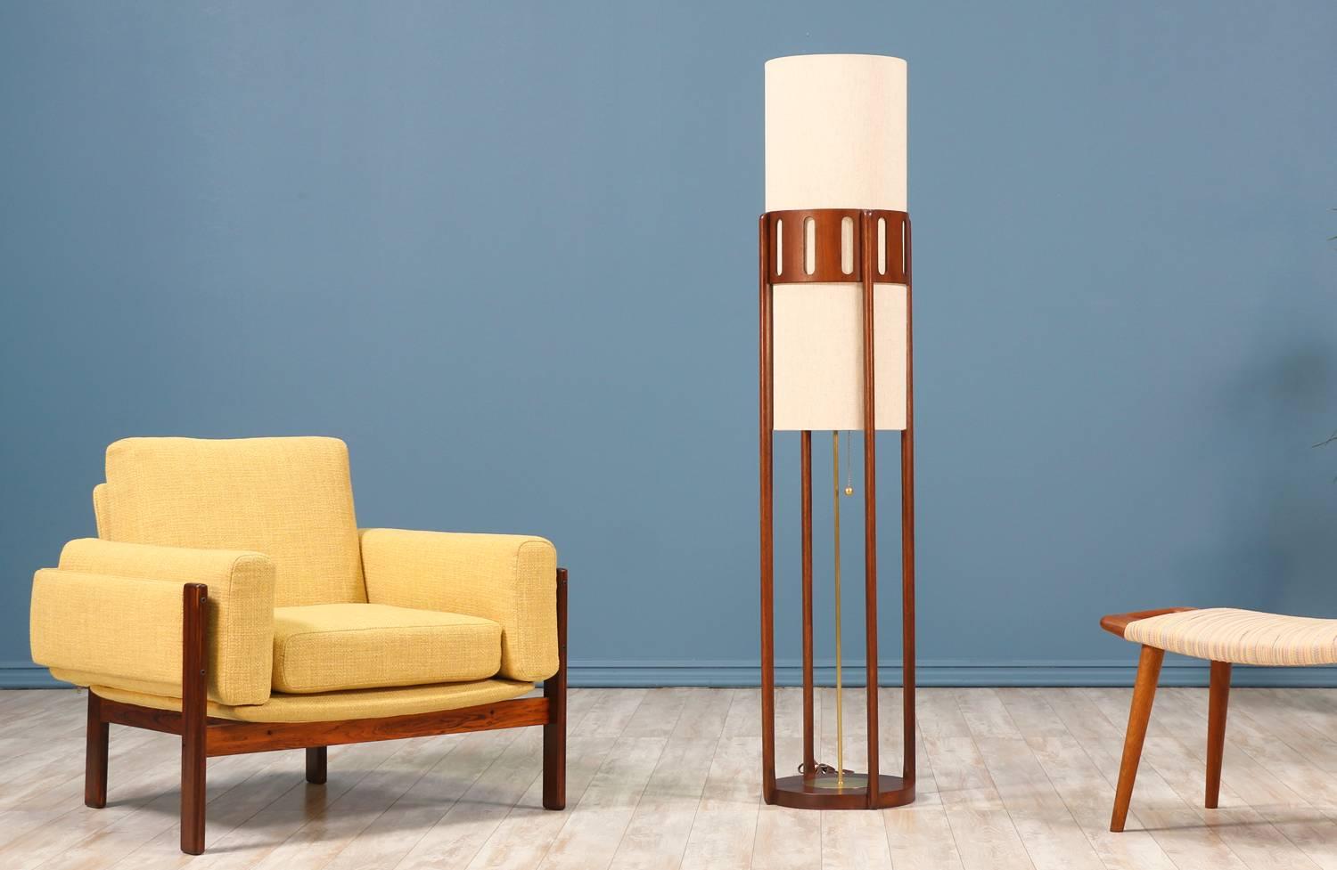 Mid-Century Modern floor lamp designed and manufactured by Modeline of California in the United States circa 1960’s. This tall cylindrical lamp features four pillars on a rounded base and carved wood detailing at the top that support a linen shade.