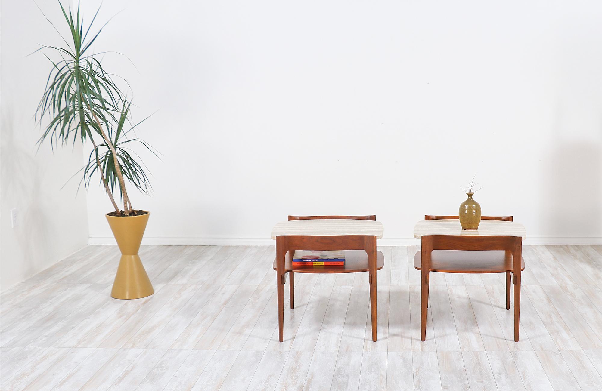 Pair of stylish modern sculpted side tables designed and manufactured by Gordon Furniture Co. in the United States, circa 1950s. This elegant set of two side tables features a softly contoured and sculpted walnut wood frames with modern lines and a