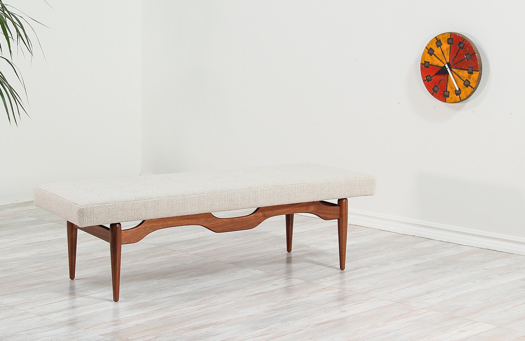 Mid-Century Modern bench designed and manufactured in the United States, circa 1950s. A comfortable modern bench featuring a sculptural solid walnut wood base and new tweed upholstery with an elegant tufted detail making an excellent option for