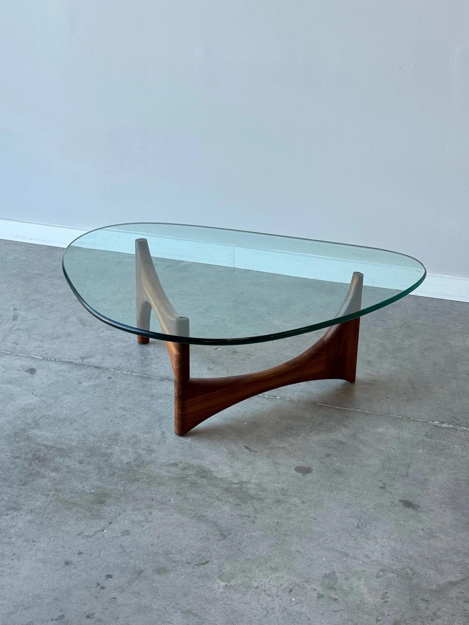 Mesa de centro escultórica de mediados de siglo, de nogal y tapa triangular de cristal, diseñada por Adrian Pearsall para Craft Associates, hacia la década de 1960. De diseño triangular y equipado con una robusta tapa de cristal. La base es de