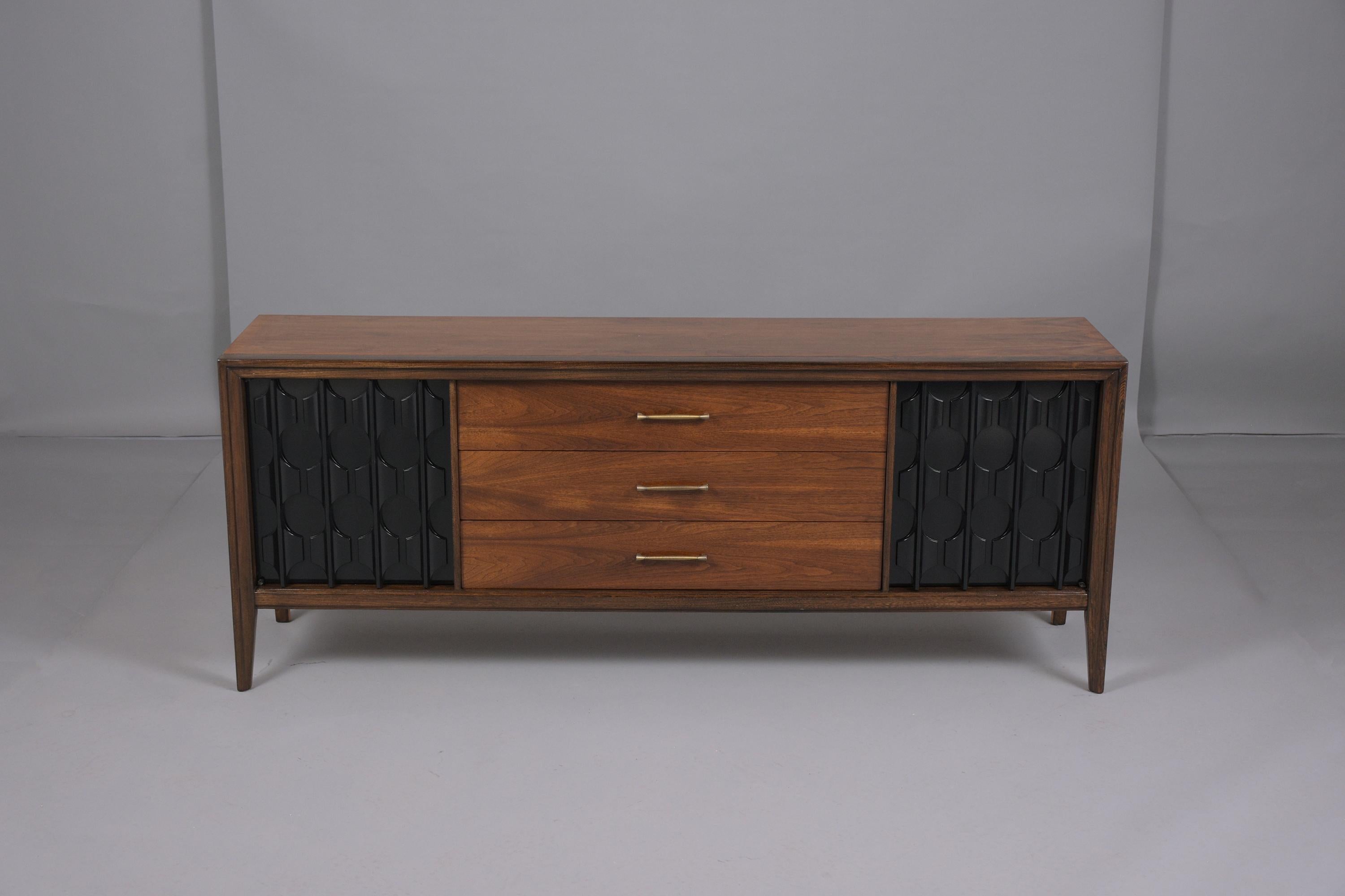 This excellent vintage 1960's mid-century credenza is hand-crafted out of walnut and has been professionally restored and finished by our craftsmen in the house. This elegant sideboard has been newly stained in a rich walnut and ebonized color