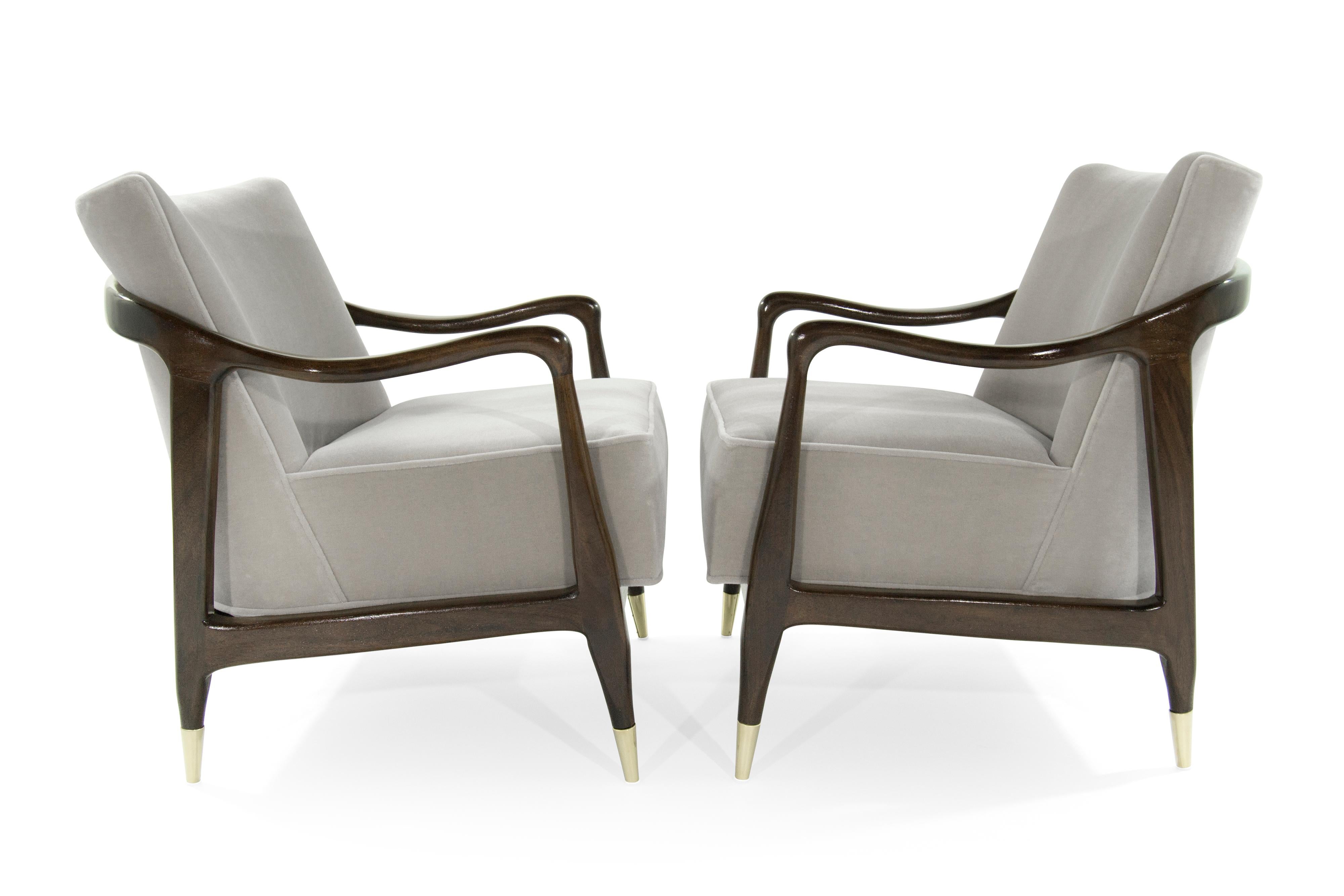 Exquisite pair of Mid-Century Modern lounge chairs featuring sculptural walnut frames, which have been expertly restored to their original integrity. They boast handcut high grade foam, as well as hand polished brass sabots.
They have been