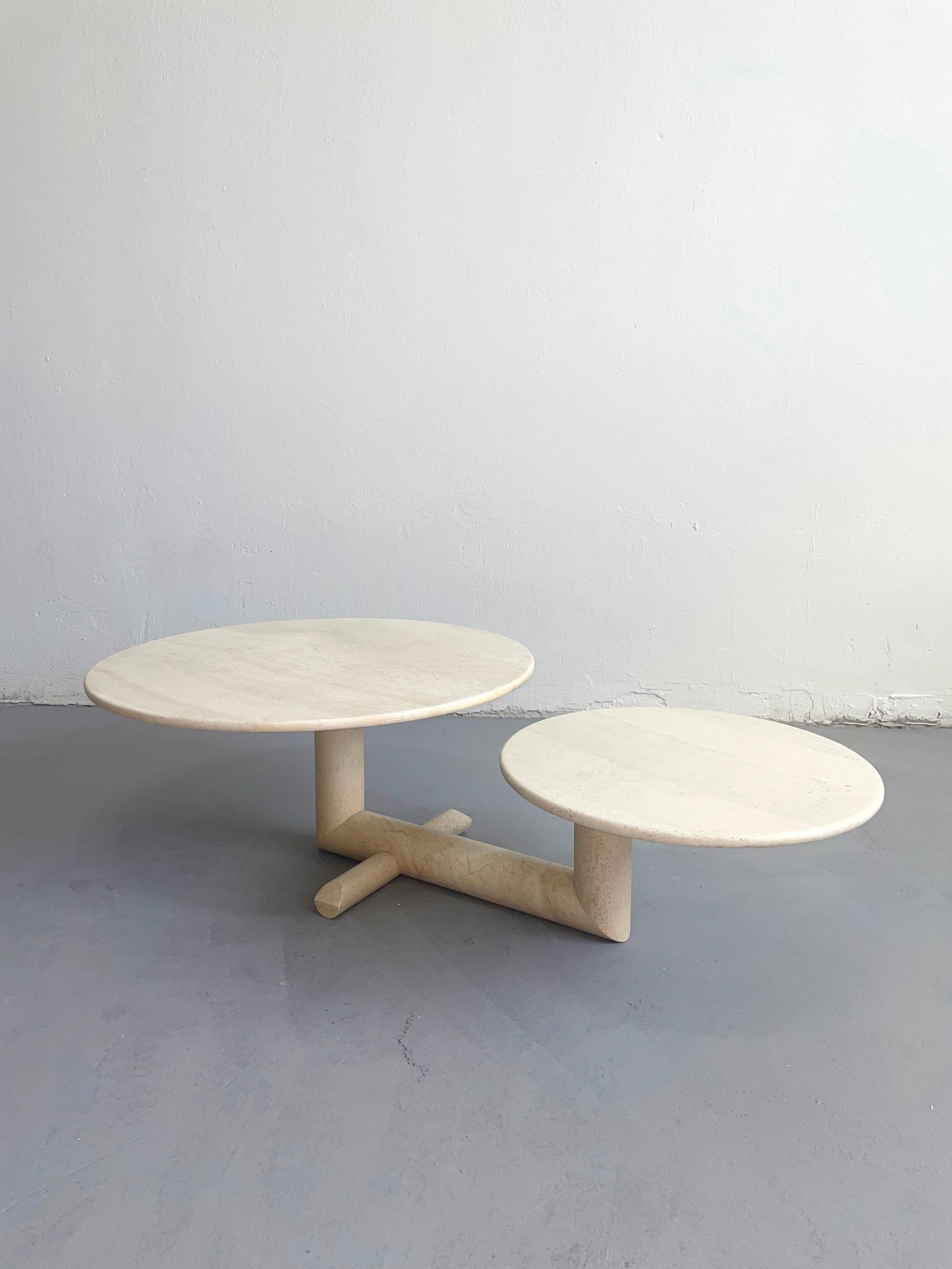 Sculptural asymmetrical travertine coffee table, manufactured in Italy in the '80s.

The table features two polished round travertine plates and a cross-shaped base.
The length of the table can be adjusted by rotating the plates (115 to 155 cm) -
