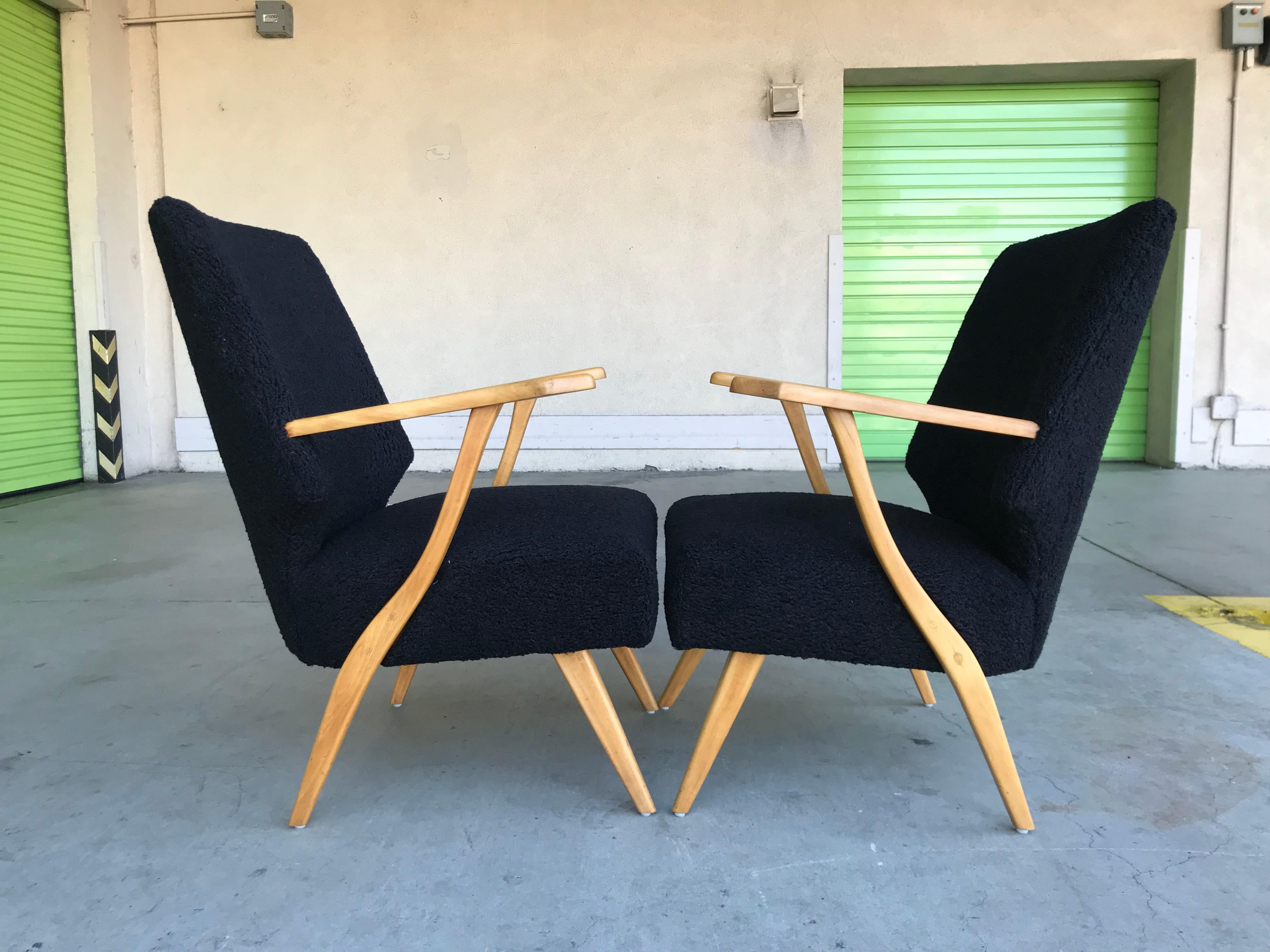 Handsome pair of lounge chairs.
Wood construction with nice sculptural arm / leg base, appears to be birch wood.
Restored with new black boucle upholstery.
Sits comfortably with snug high-backrest. 
Solid, sturdy and stout.
Presents well for any
