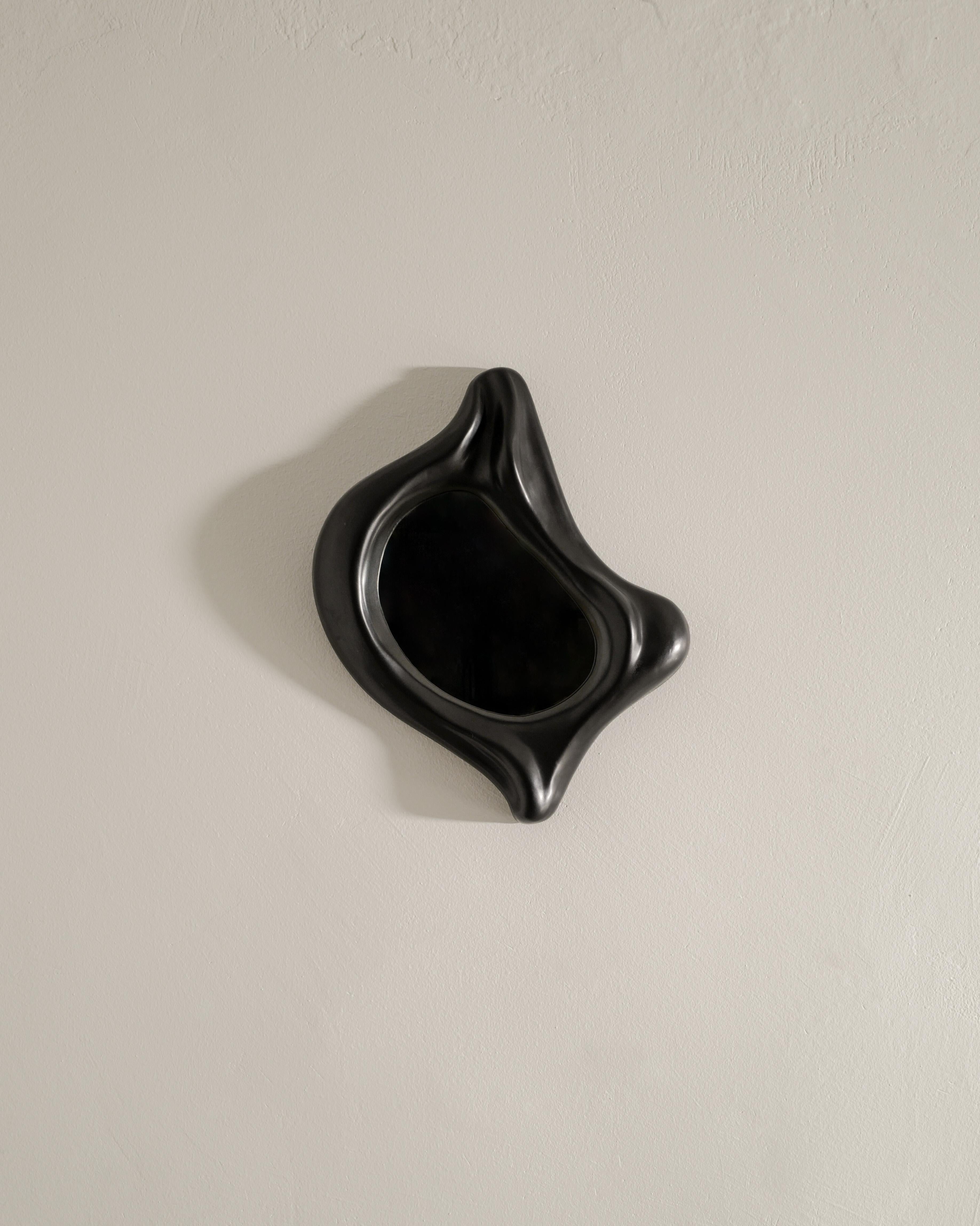 Seltener schwarzer Keramik-Wandspiegel aus der Mitte des Jahrhunderts im Stil von Georges Jouve, hergestellt in Frankreich in den 1960er Jahren. In gutem Originalzustand. 
Auf der Rückseite befinden sich zwei diagonal zueinander verlaufende Löcher,