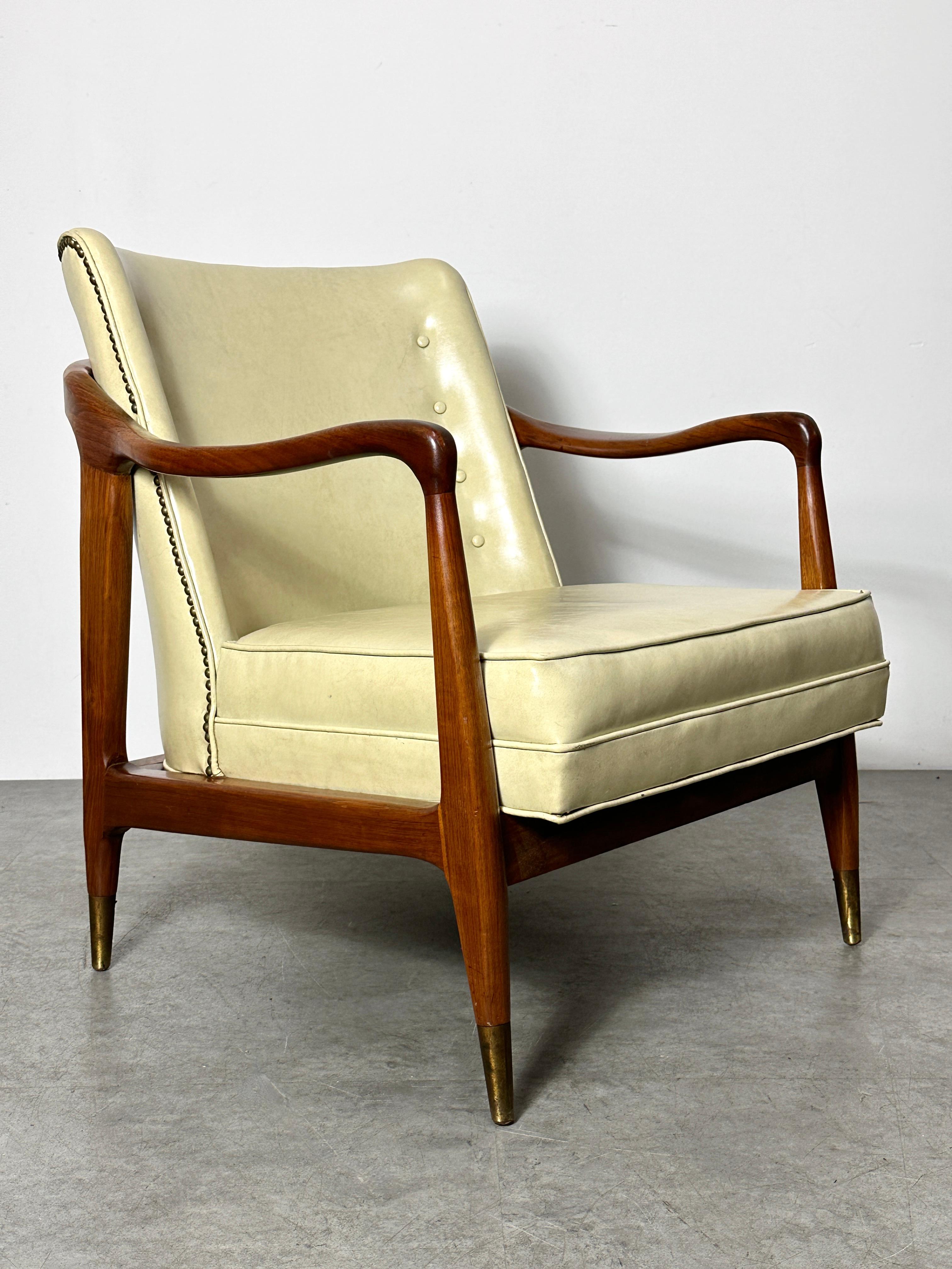 1950s lounge chair in the style of Gio Ponti
Sculptural walnut frame with brass tipped feet
Original Naugahyde upholstery in ivory with tufted back and brass nailhead accents
