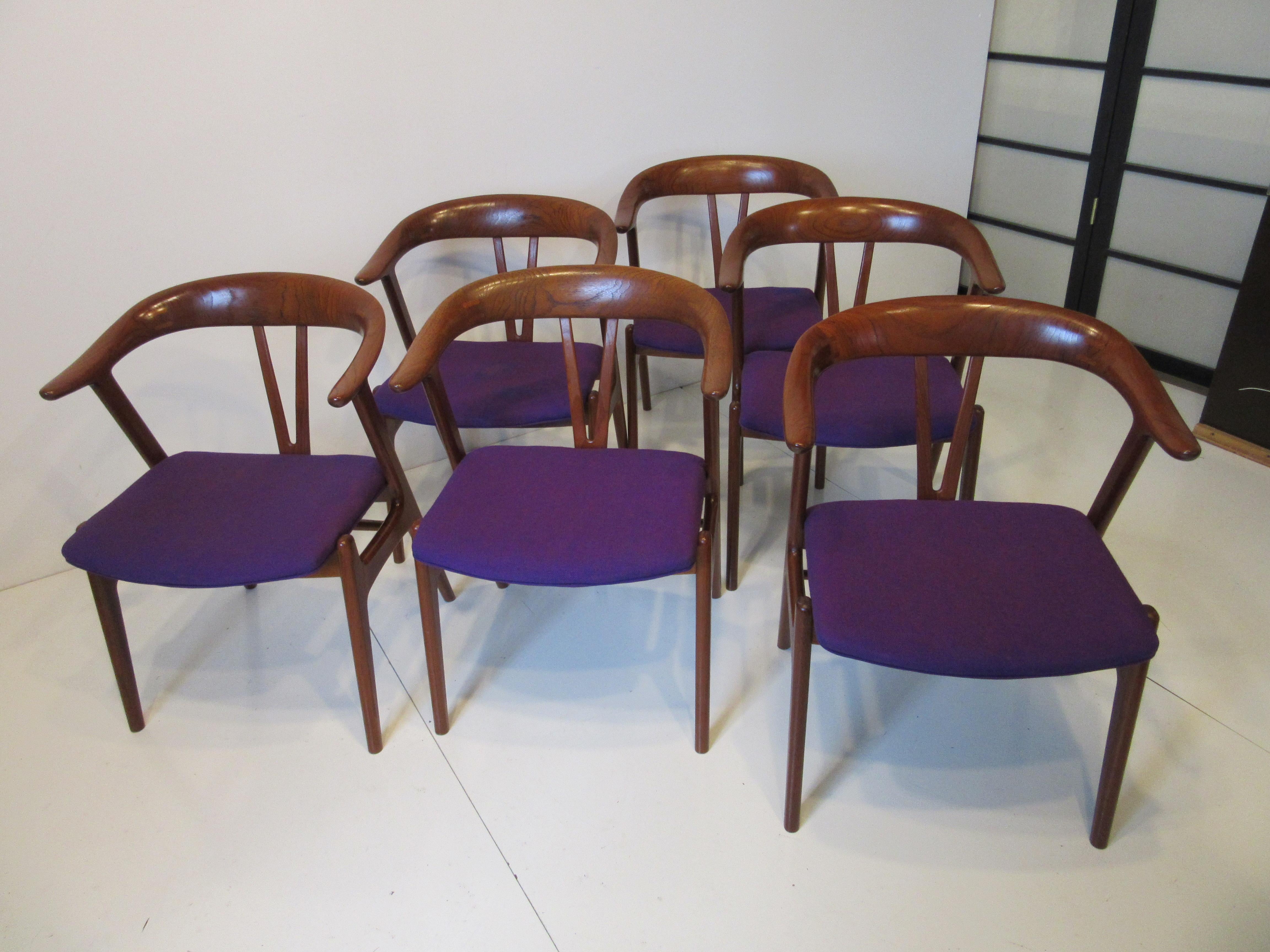 A set of six sculptural walnut dining chairs with bull horn styled back curving into the arm rests having a V shaped spine and great angled legs. The back rests show wonderful ring wood graining with great joinery the seat bottoms are upholstered in