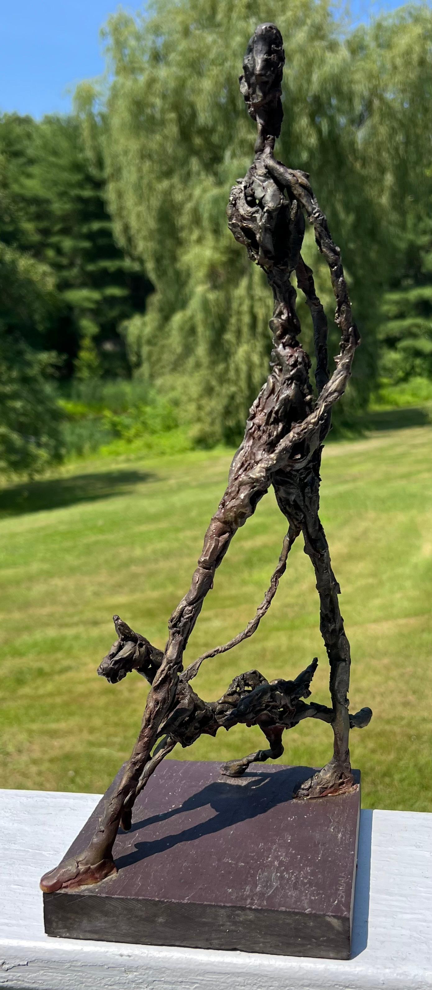 Wire and metal sculpture of a woman walking her dog.  In the style of Alberto Giacometti, this piece is signed Sarala on the base.  