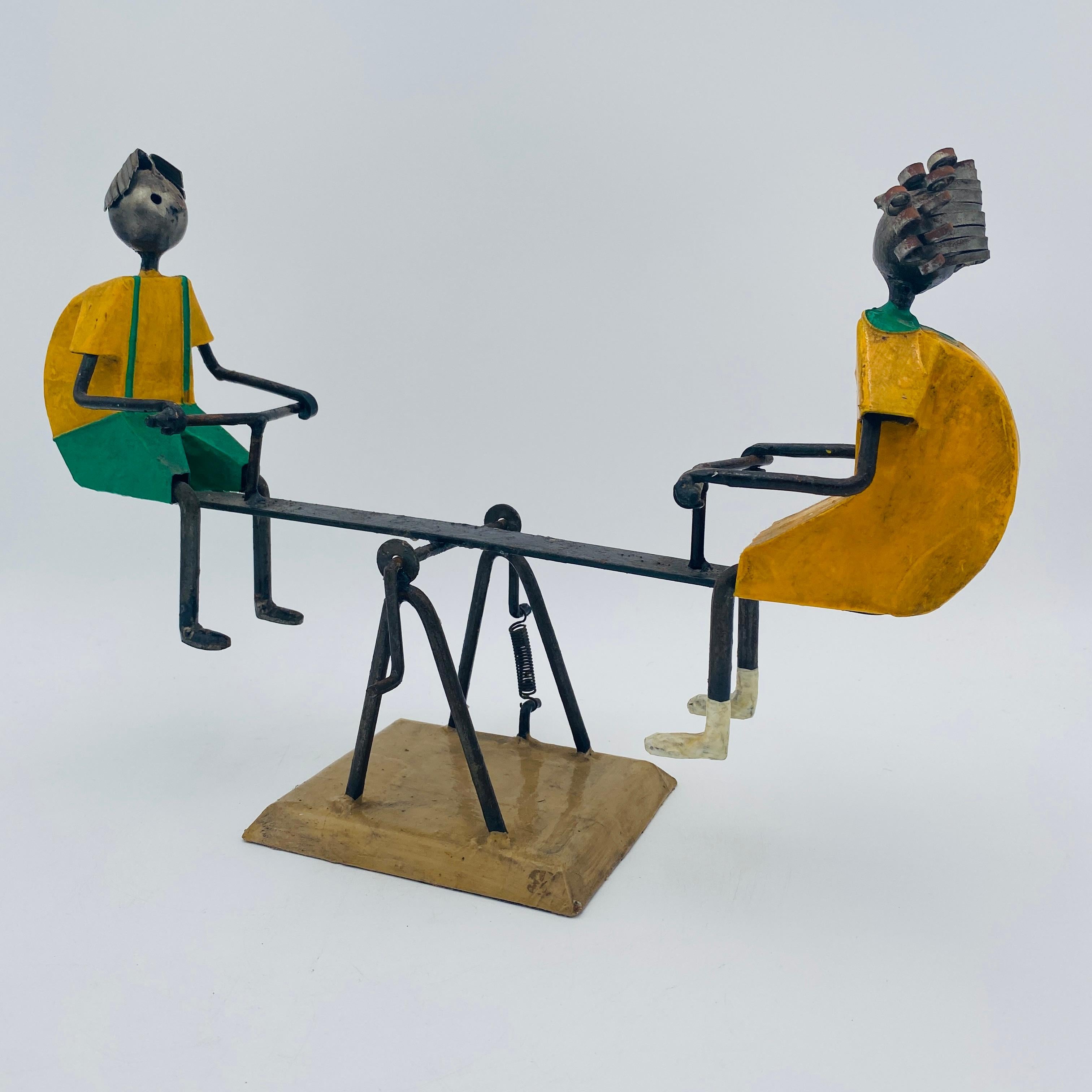 An incredible mid-century modern sculpture by listed Mexican artist Manuel Felguérez depicting two children on a seesaw. The sculpture, depicting a boy and girl on a seesaw, or teeter totter, is comprised of metal, papier mâché, and wood and was
