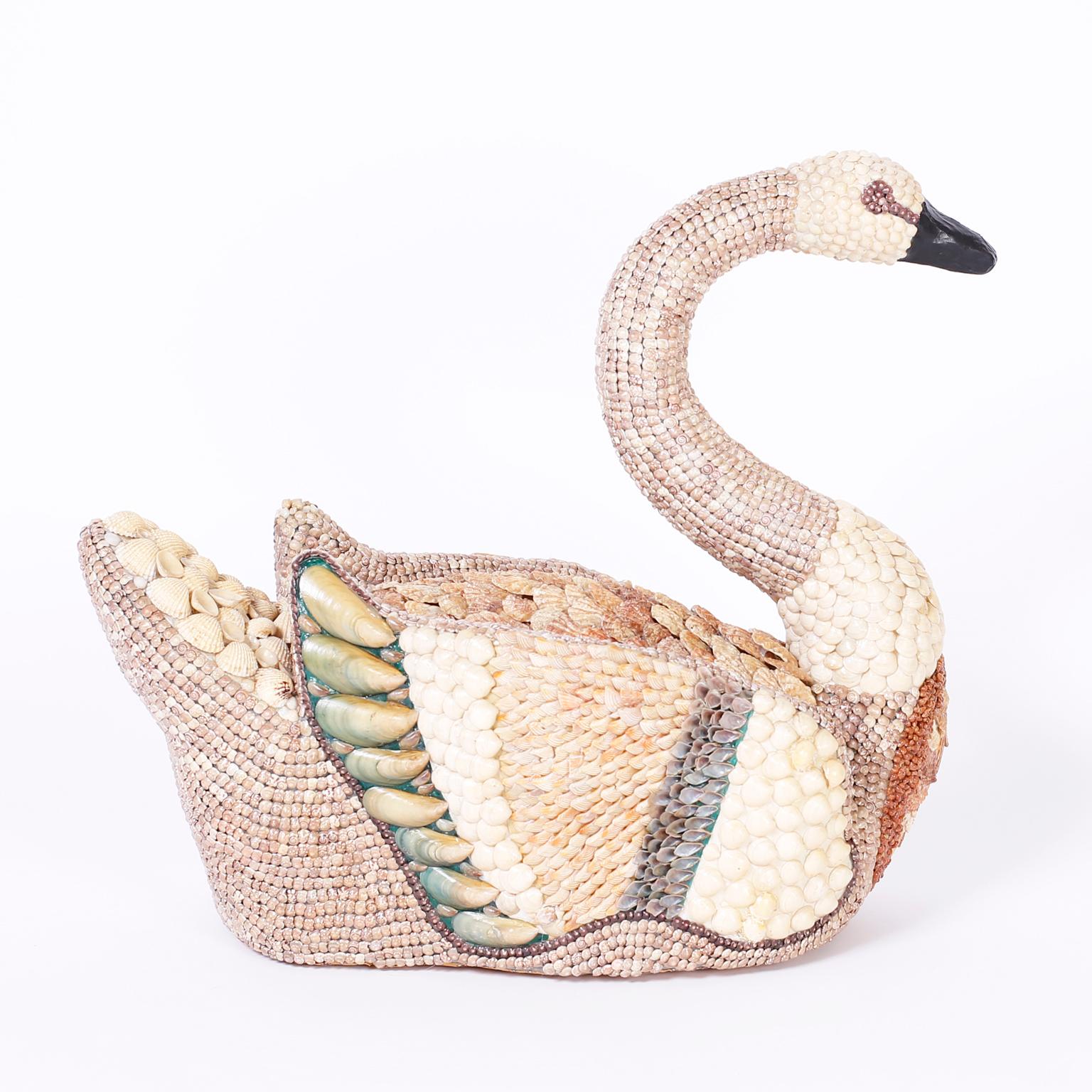 As if floating on a pond this lofty life-size swan is completely encrusted with exotic sea shells over a composition form.