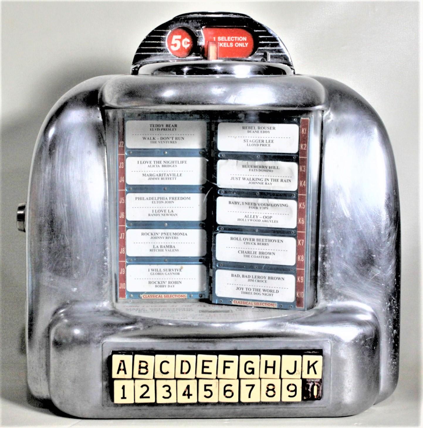 Dieser frühe, an der Wand montierte, münzbetriebene Jukebox-Musikwähler ist völlig unmarkiert, wird aber der Seeburg Corporation of the United States um 1955 im Stil des Maschinenzeitalters zugeschrieben. Seeburg hat eine 