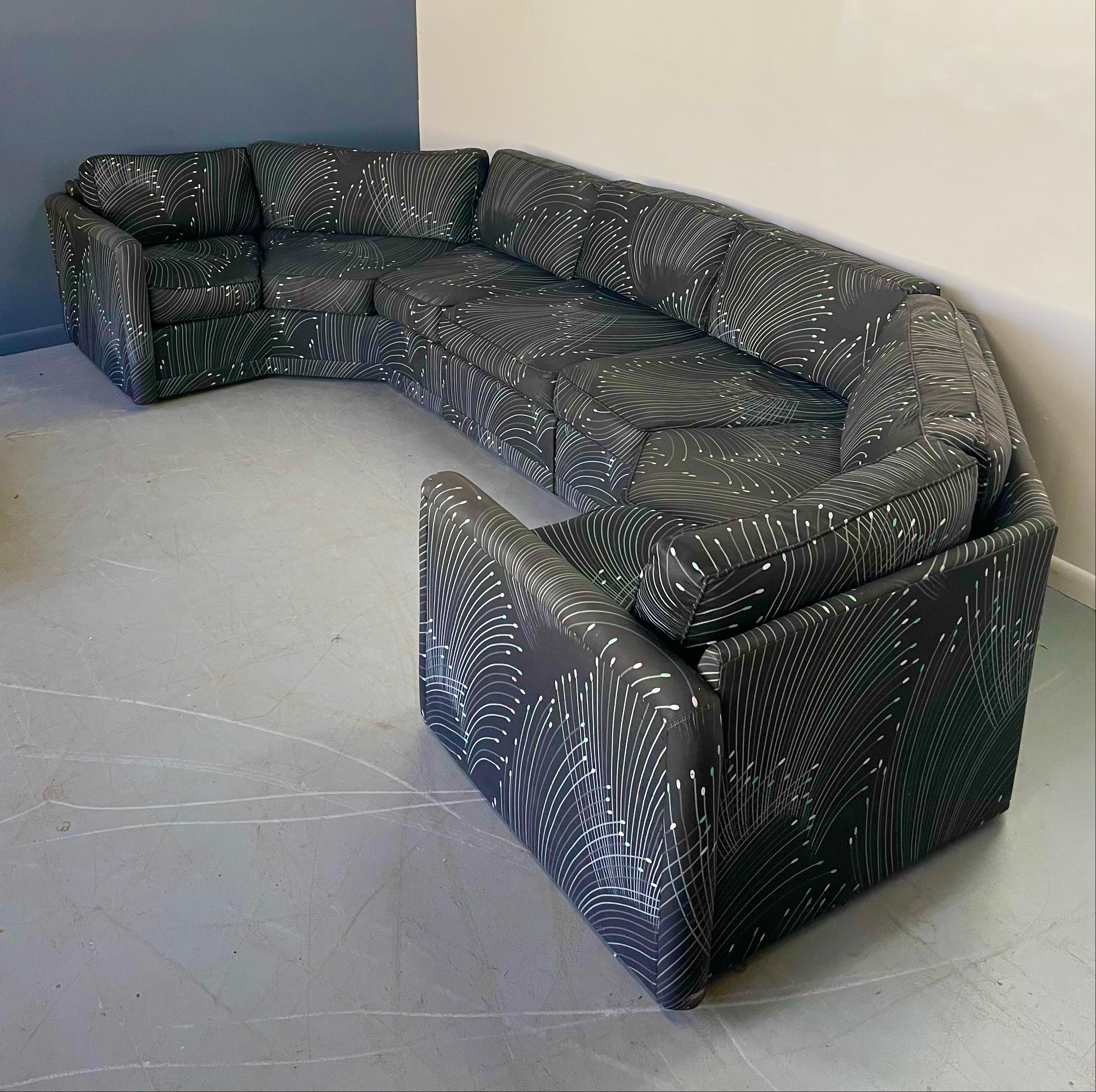 A large and impressive semi circular sofa designed in the style of Milo Baugman and produced by Carsons in the 1970s. It features 2 angular sections and a single section in the middle that can be removed to create a smaller profile, retaining the