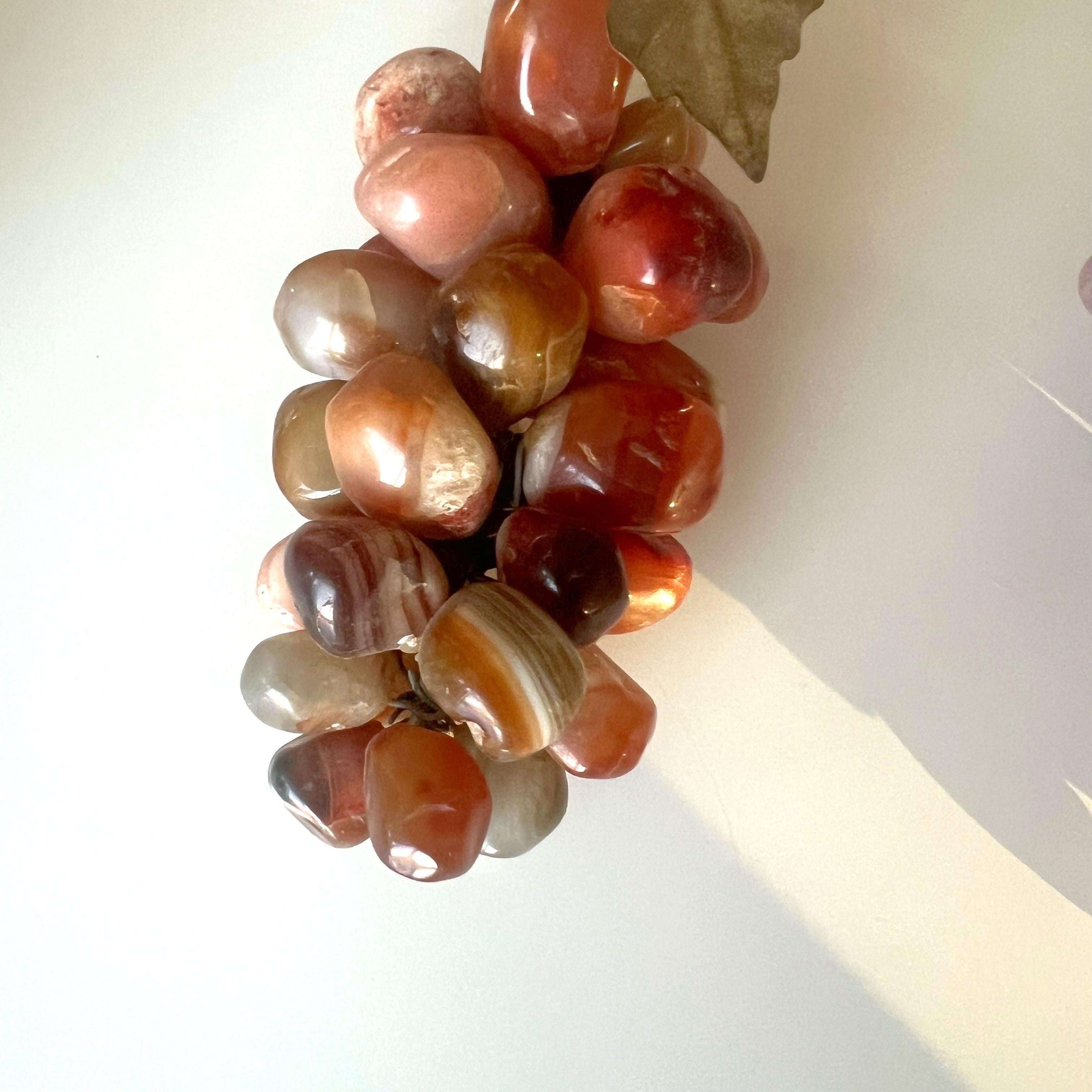 Grandes racimos de uvas de mediados del siglo XX en cornalina y amatista 
: La Cornalina es una piedra que representa el calor, la fogosidad, la vida, la vivacidad, la fuerza, la valentía, el coraje al hablar en público y la creatividad. Se cree que