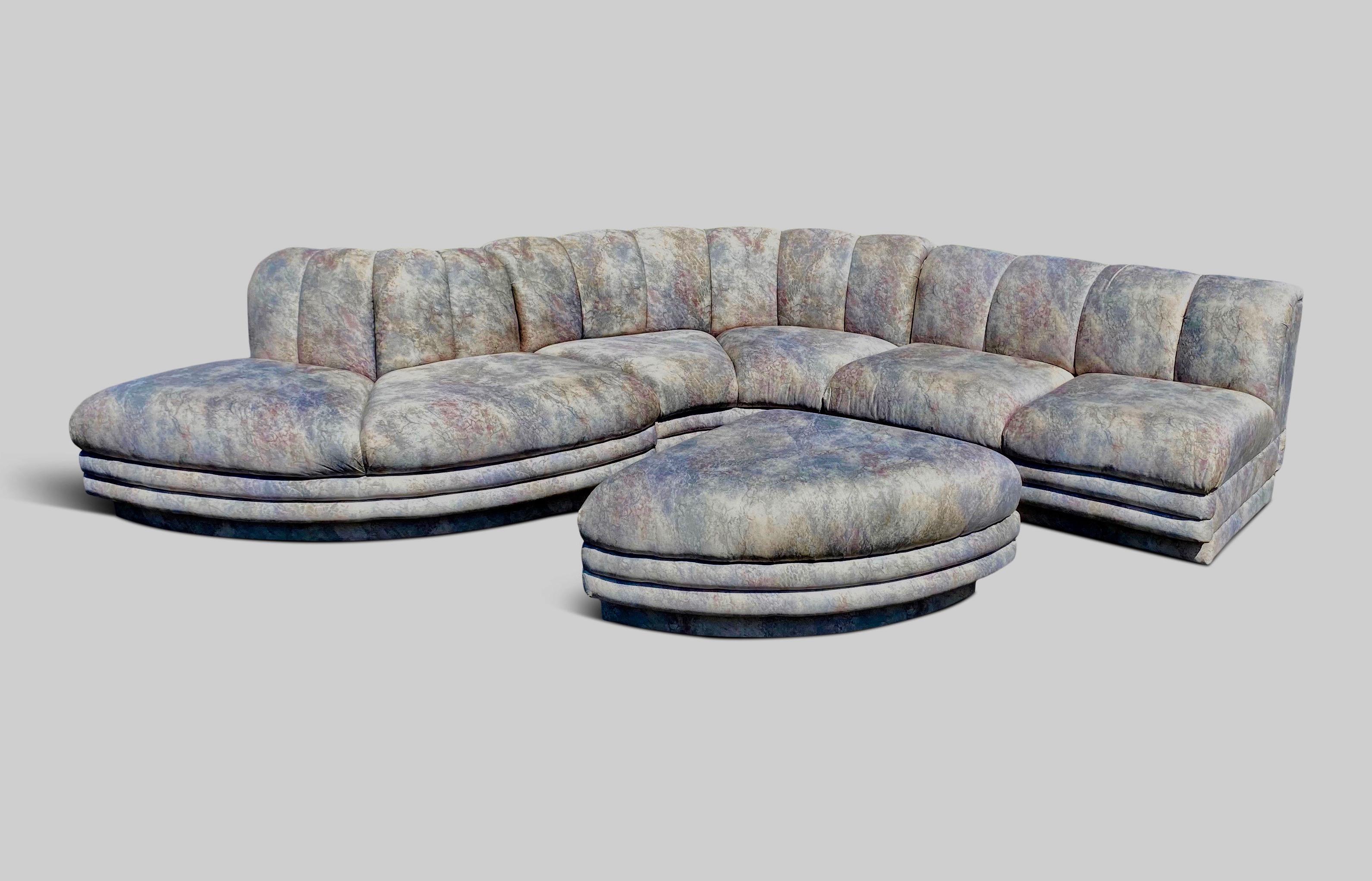 1970s large Baughman style serpentine sofa with a plinth base and a channel back. This sofa has a built in ottoman in a 1970s fabric. The sofa is in wonderful structural condition, the fabric could use an update. 

We would be pleased to reupholster