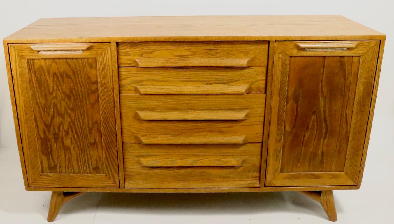 Organic and rustic modern style server, credenza, in oak, - Designed by Jack Van der Molen, Americana Casual for the Jamestown Lounge Company. This cabinet features four center drawers, flanked by doors which swing open to revel shelved storage.