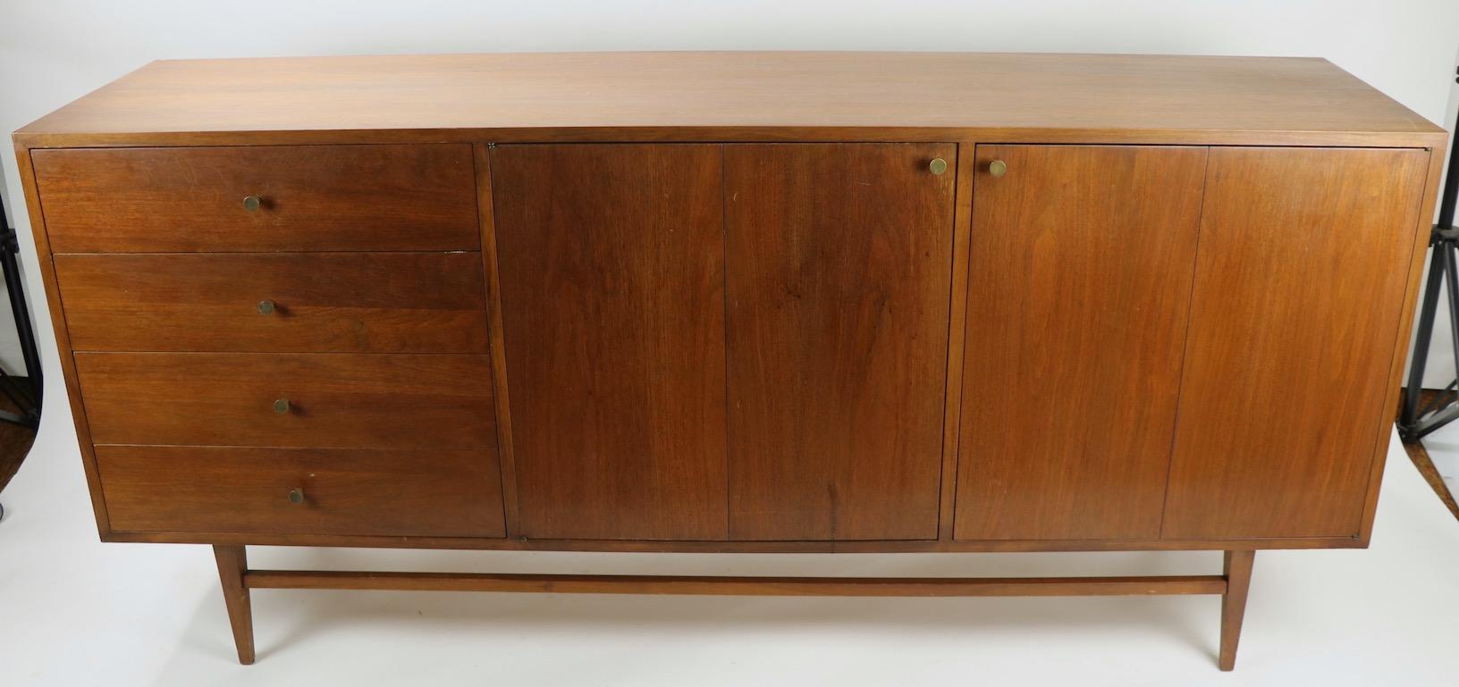Nice Mid-Century Modern credenza having a large cabinet bottom and a tall vertical display shelf top element. The shelf has its original white glass insert surfaces and four thin drawers The bottom features four drawers on one side, the top drawer