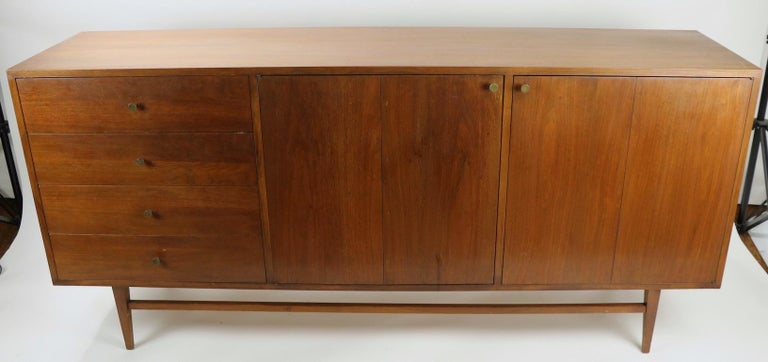 Nice Mid-Century Modern credenza having a large cabinet bottom and a tall vertical display shelf top element. The shelf has its original white glass insert surfaces and four thin drawers The bottom features four drawers on one side, the top drawer