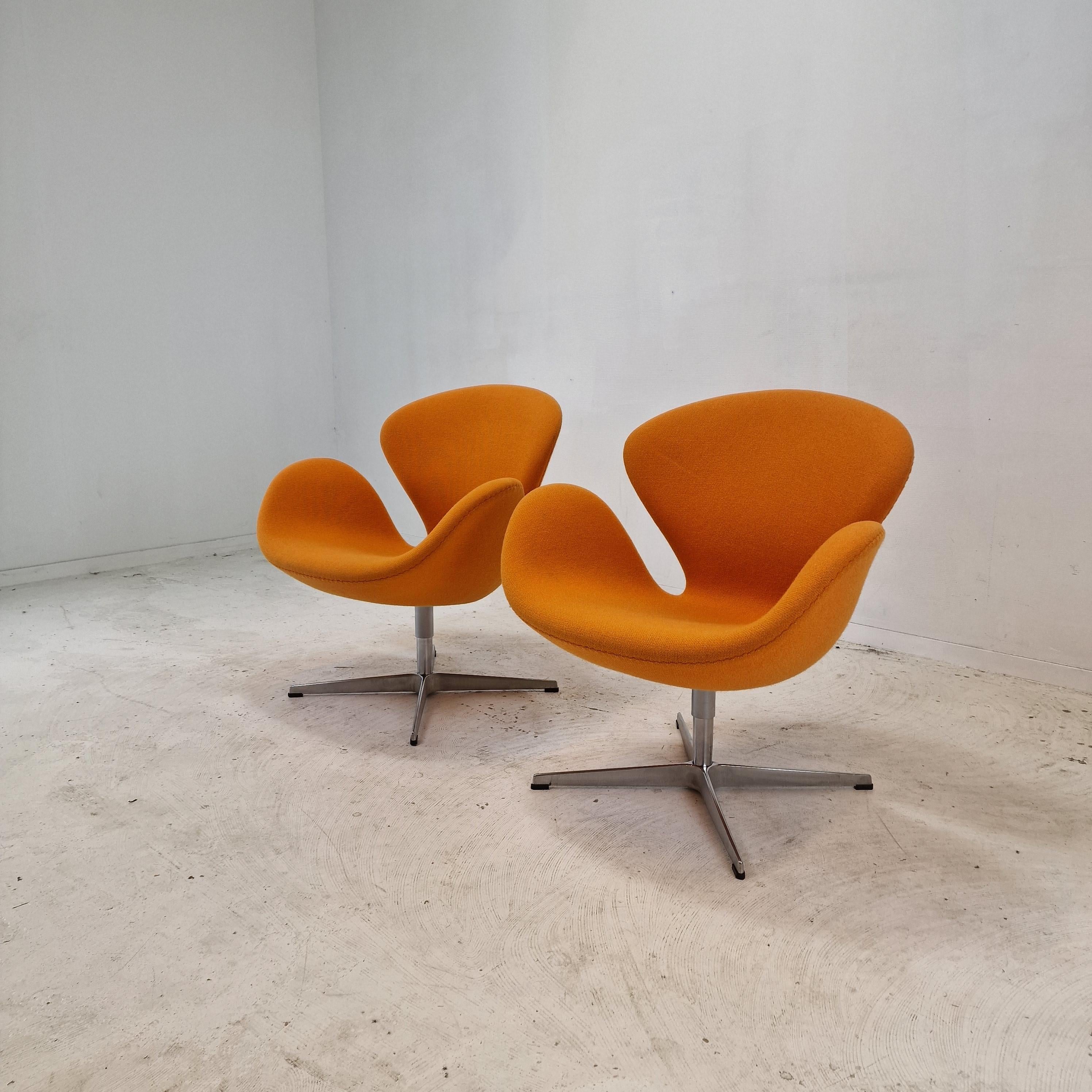 Beautiful set of two original Swan Chairs. 

These Swan chairs were designed in the 1950s by Arne Jacobsen for the SAS Hotel in Copenhagen and produced by Fritz Hansen.

The chairs feature a wonderful original orange upholstery, the high quality