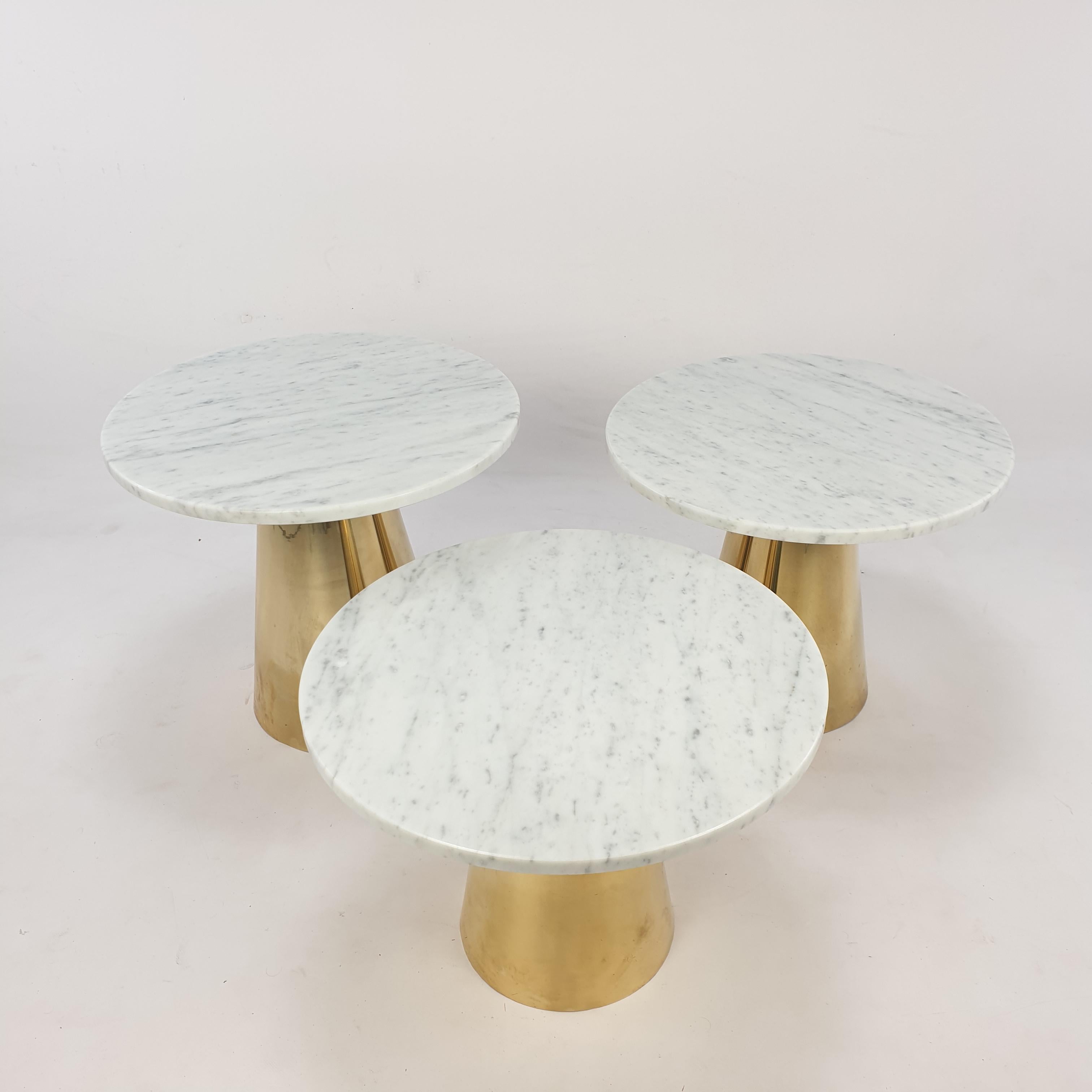Lovely set of 3 Italian coffee or cocktail tables. They have a Carrara marble round plate with a brass base. All tables have a different hight, the plates have the same size.