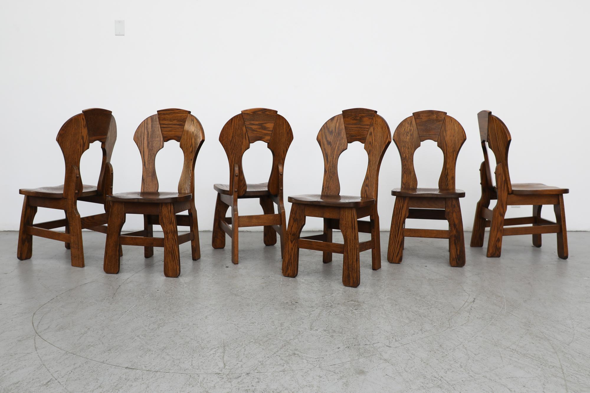 Beautiful set of 8 Brutalist dark toned oak dining chairs with ornate backrests and carved, organic legs. Lightly refinished in otherwise original condition with some  visible wear consistent with age and use, including some missing pegs. Set price. 