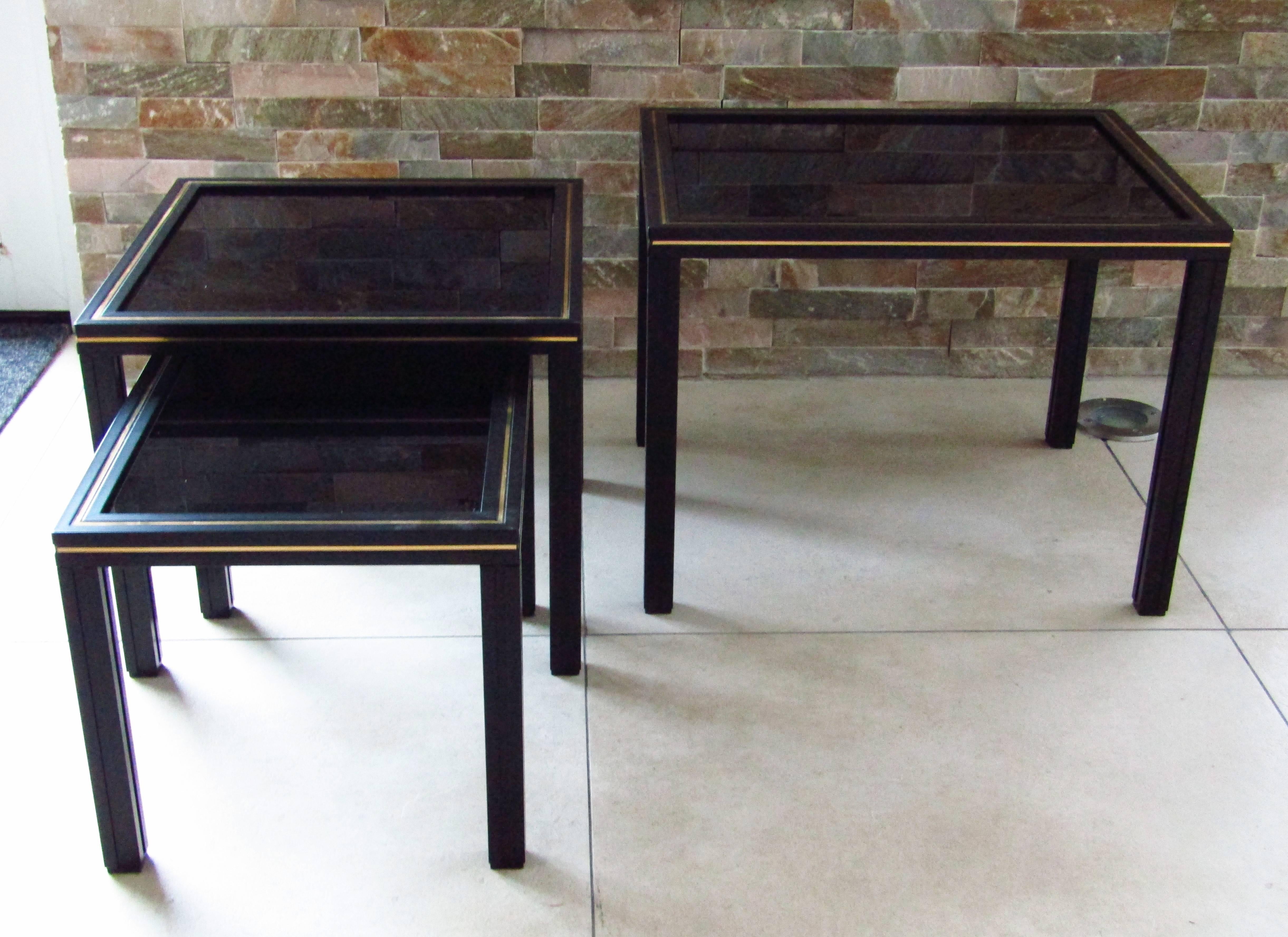 French vintage set of three nesting tables by Pierre Vandel in black lacquered aluminium with brass accents and black glass tops. Signed on top.

The middle table measures 13 7/8