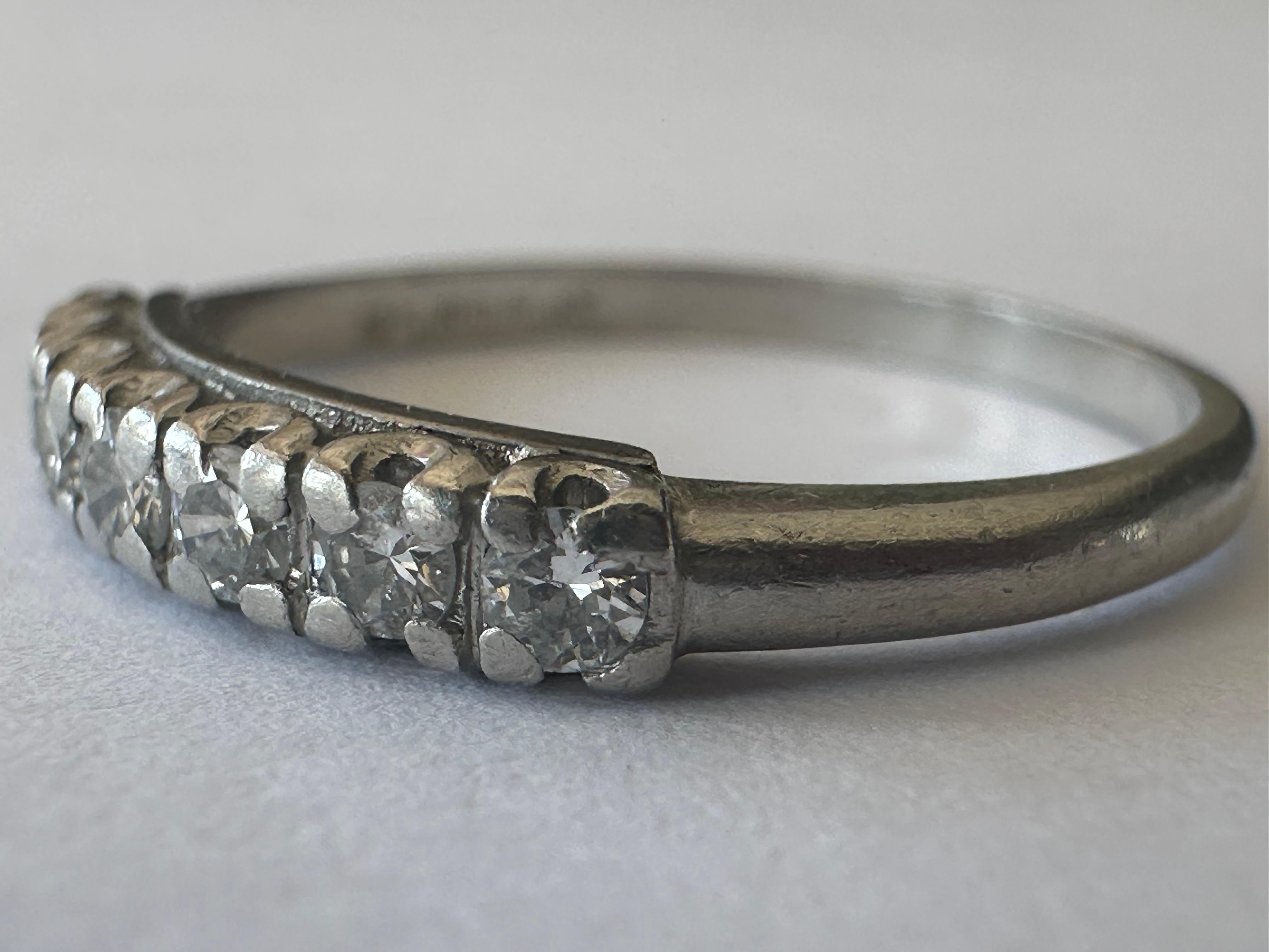 Seven round diamonds totaling approximately 0.15 carats F color SI1 clarity shimmer across the top of this classic mid-century band handcrafted in platinum. The width of the top of the band measures 3.1mm. 