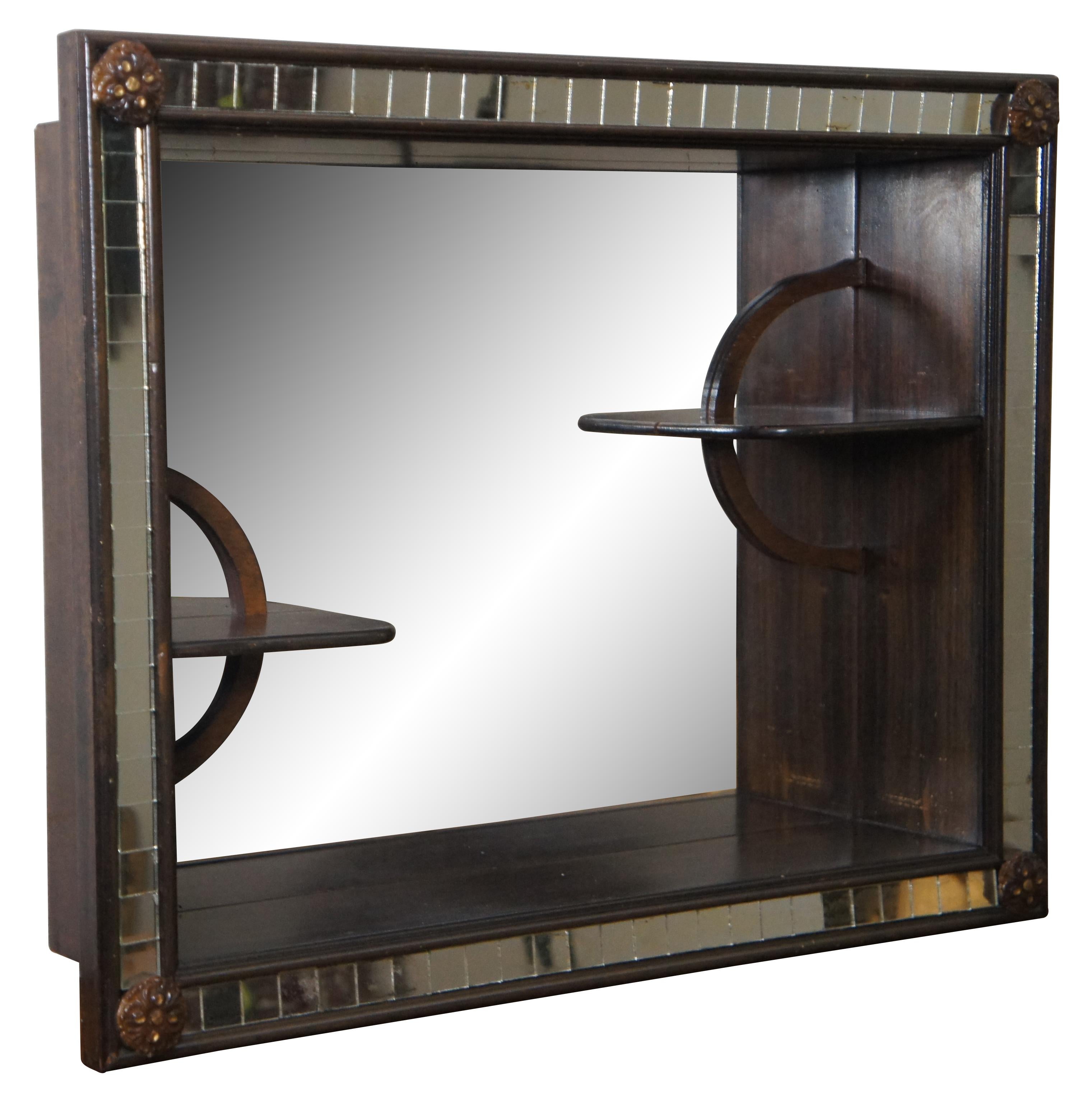 Vintage wooden wall hanging shadowbox shelf featuring a mirrored back accented with a pair of smaller offset shelves and framed with square mirror tiles and floral medallions at the corners. circa mid 20th century. Stamped 227 on back.