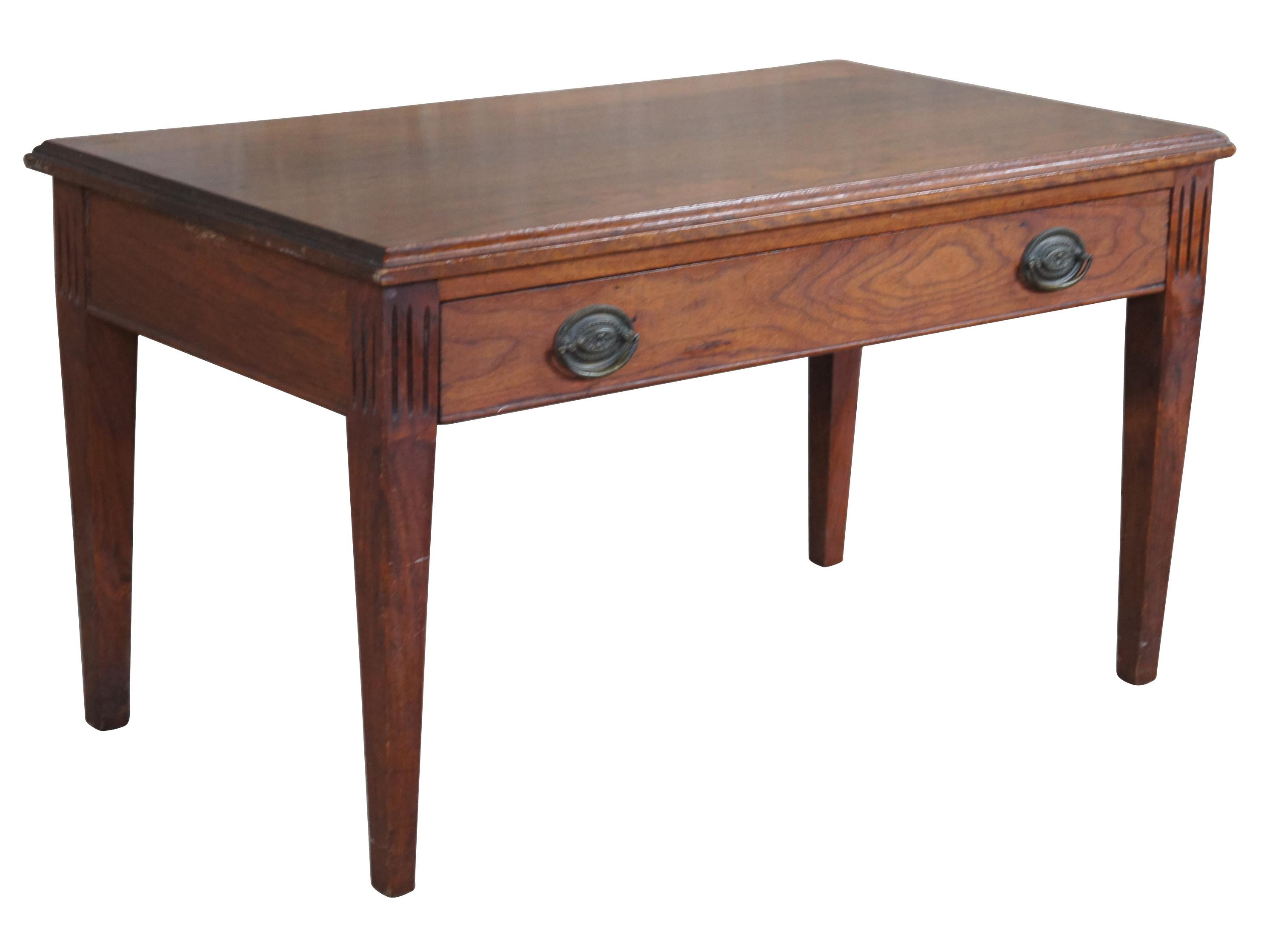 Mid-20th century Sheraton or Federal style bench. A rectangular form made from walnut with a large central rabbit joint drawer featuring oval brass hardware. The bench is supported by square tapered legs with fluted accent along the top. Its