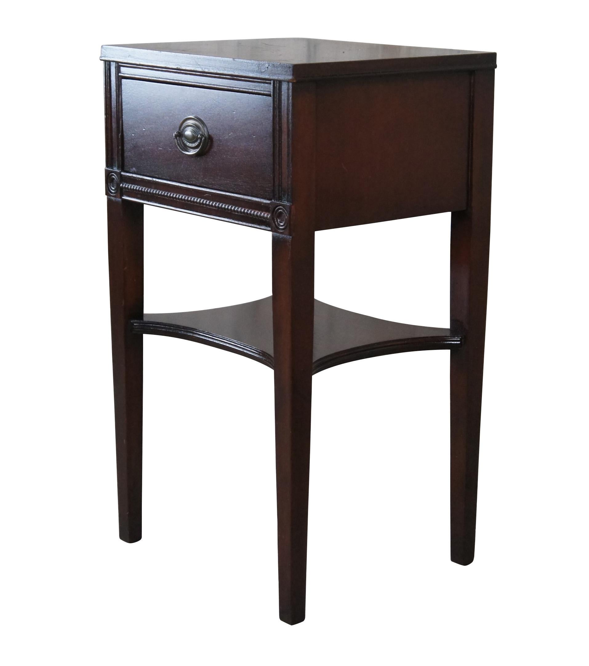 Sheraton style bedside table, circa mid 20th century.  Made from mahogany with one dovetailed drawer, beaded trim and lower shelf between square tapered legs.  

Dimensions:
16