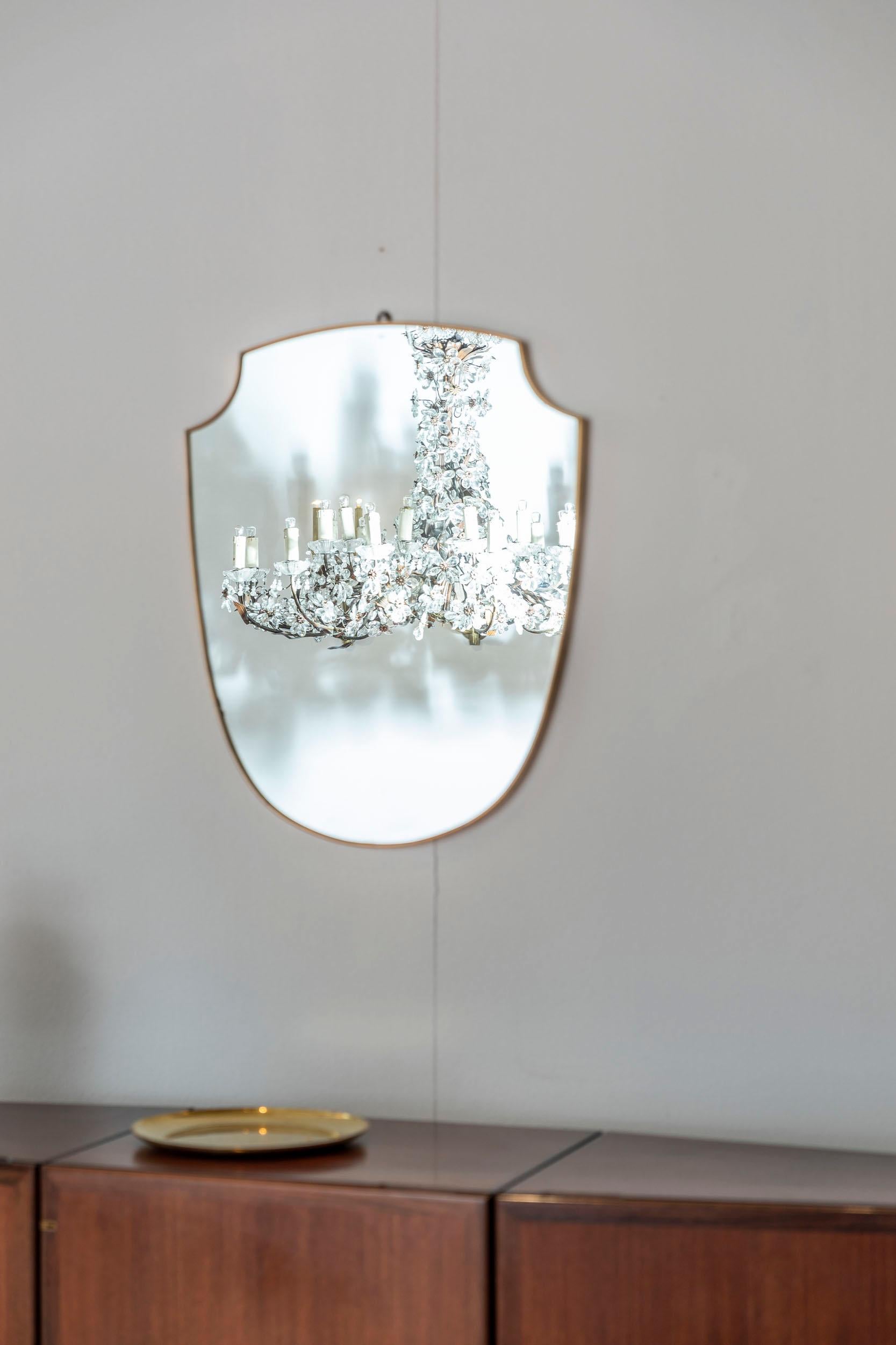 Mid-century shield mirror with brass frame.
