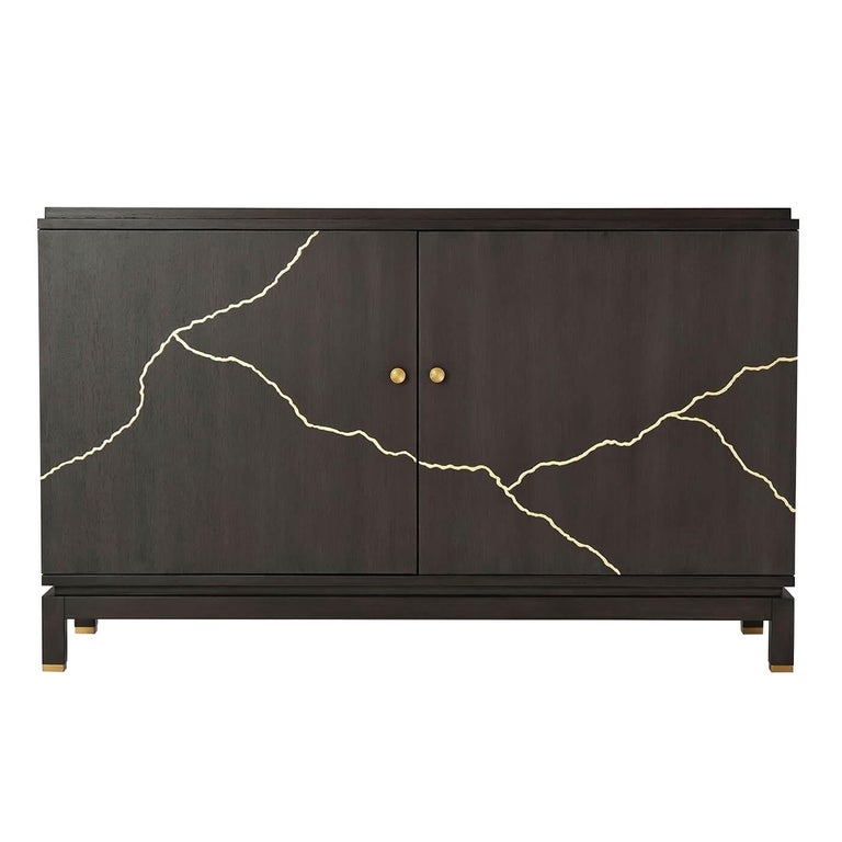 A modern midcentury side cabinet with mahogany veneer and Kintsugi gilt decoration. The cabinet with two doors enclosing two sections each with an adjustable shelf, and raised on a recessed base with square legs.

Dimensions: 52